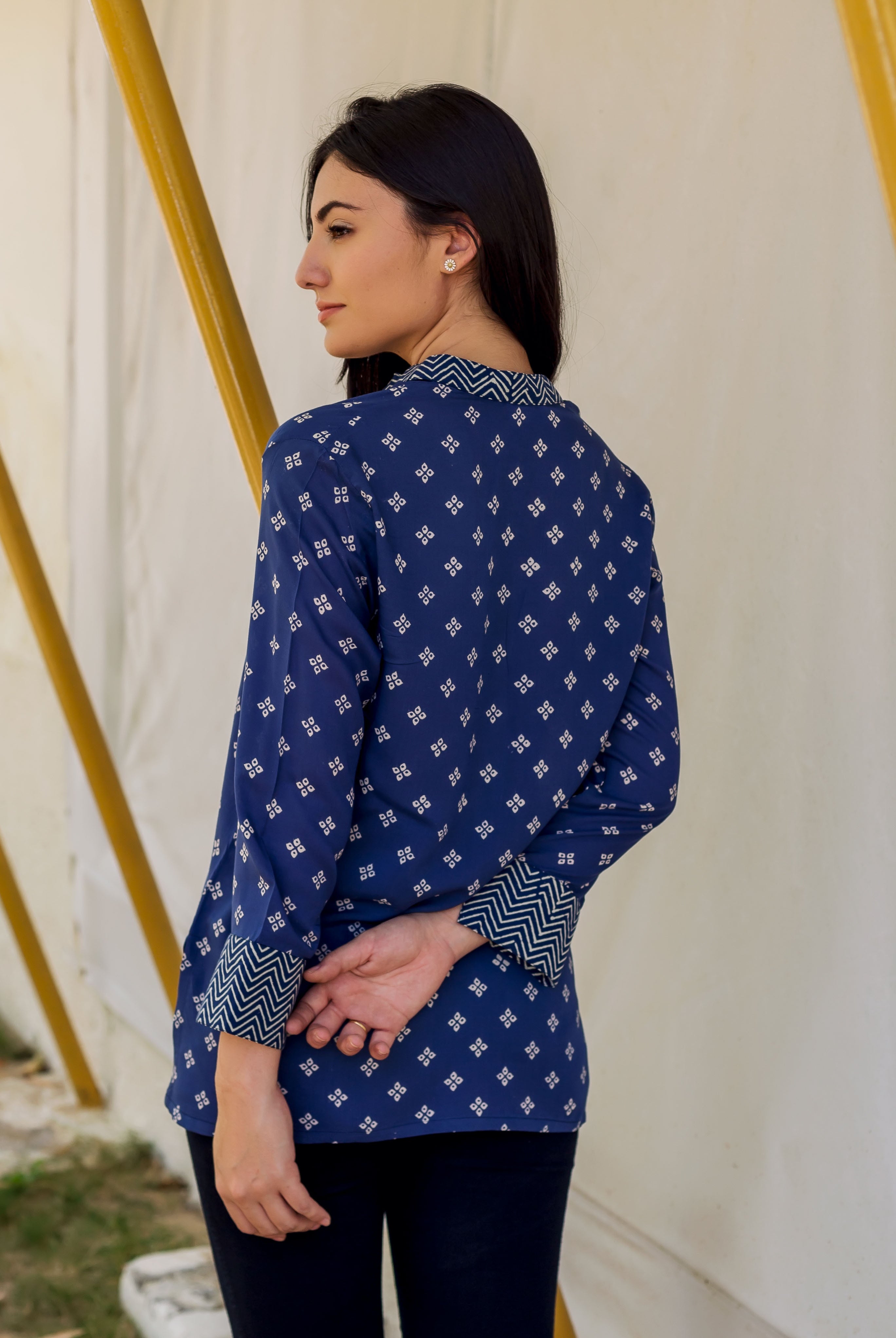 Side view of woman in a blue top with white geometric print and chevron cuffs.