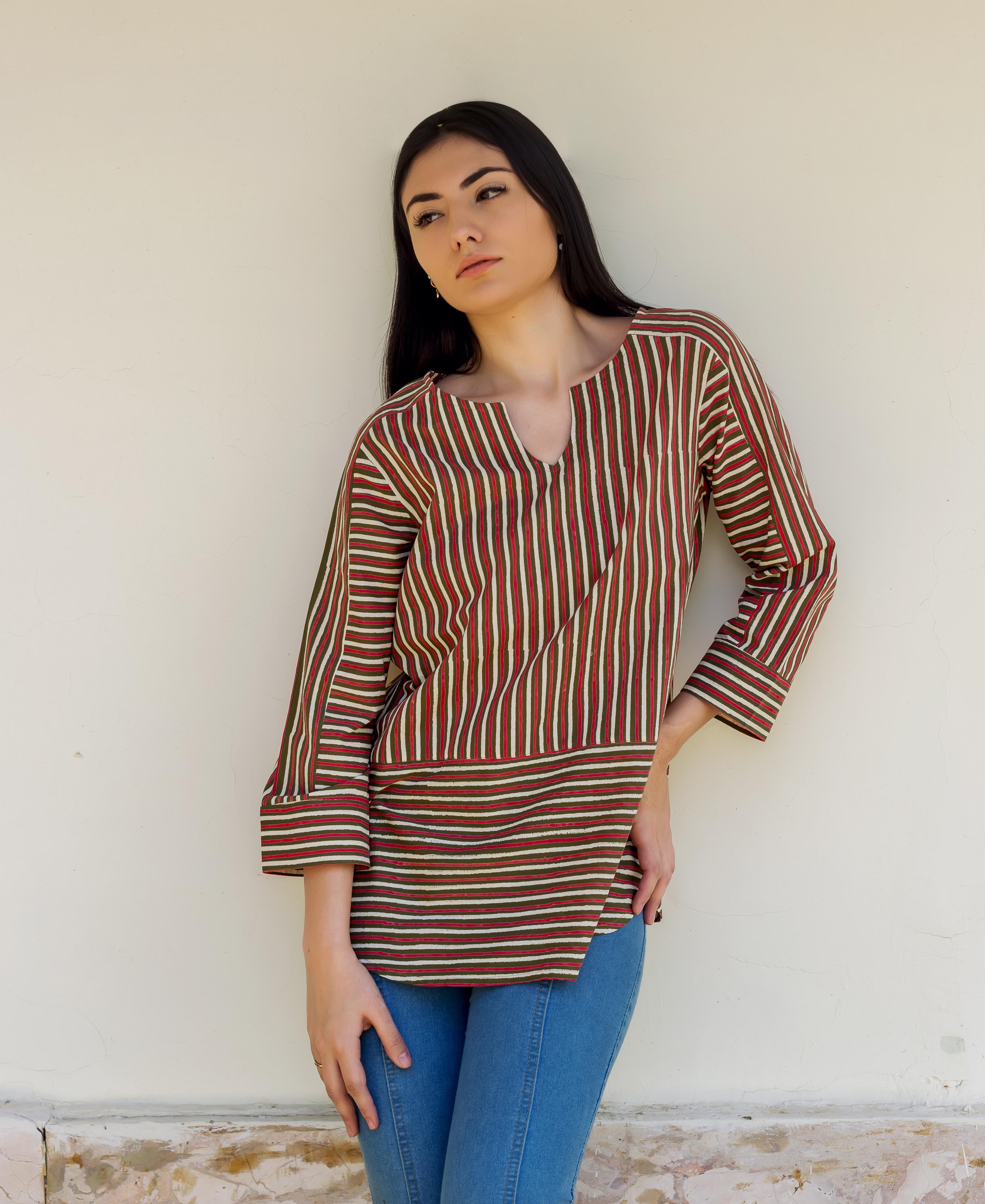 Woman models olive green and red striped tunic with contrasting vertical and horizontal patterns.