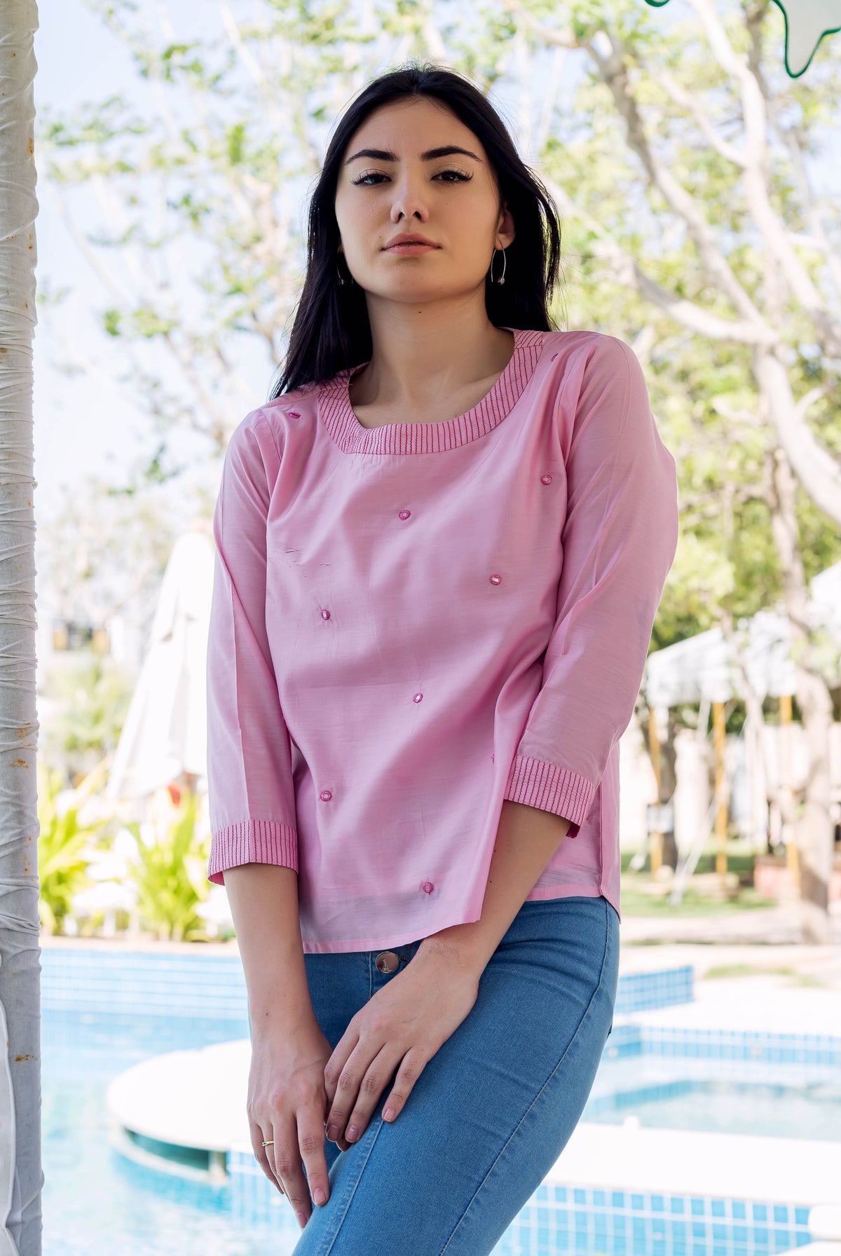 Pink chanderi embroidered top on model with embellishments and striped neck and cuffs.