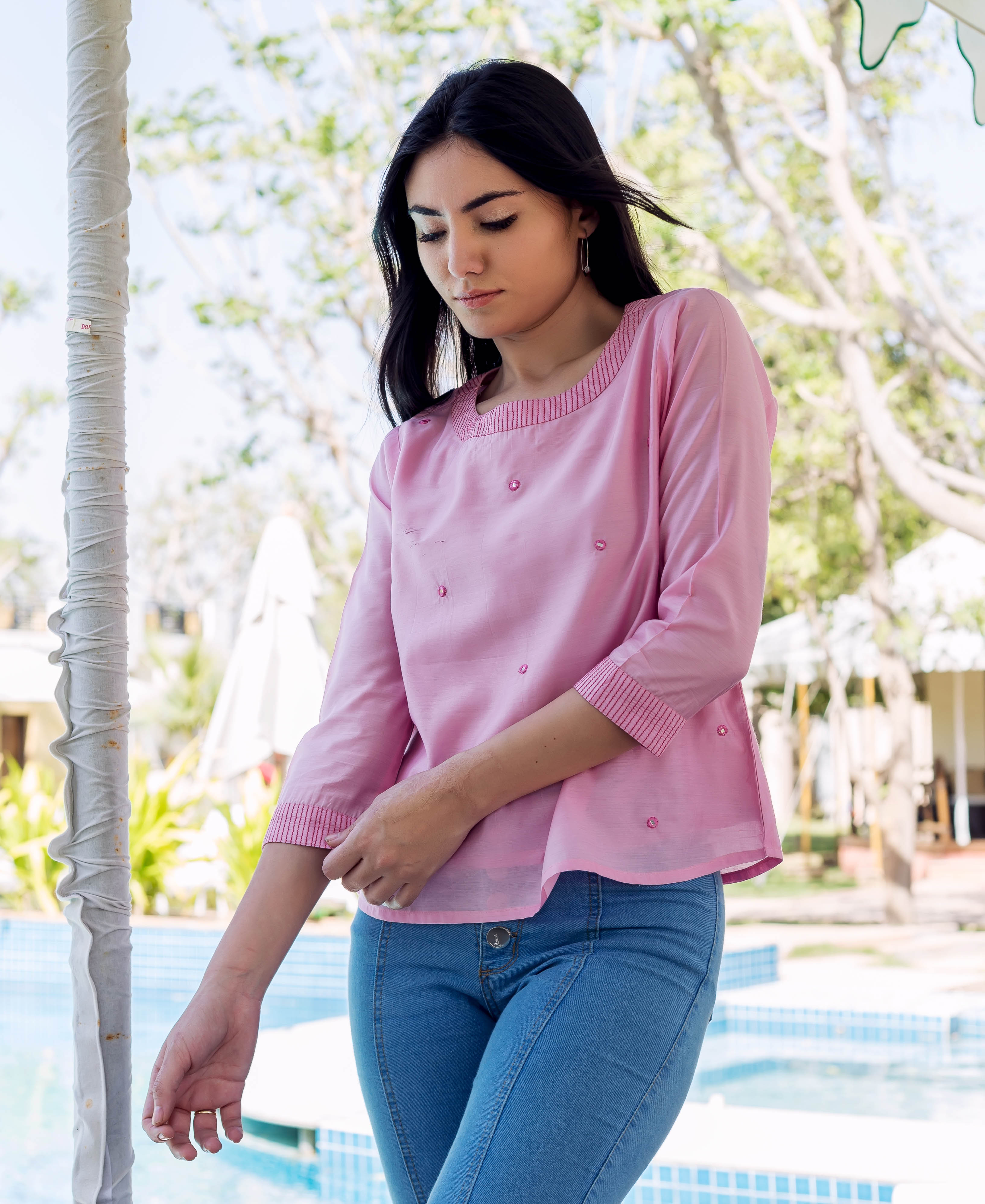 A woman wearing a pink chanderi embroidered top with a round neckline and three-quarter sleeves.