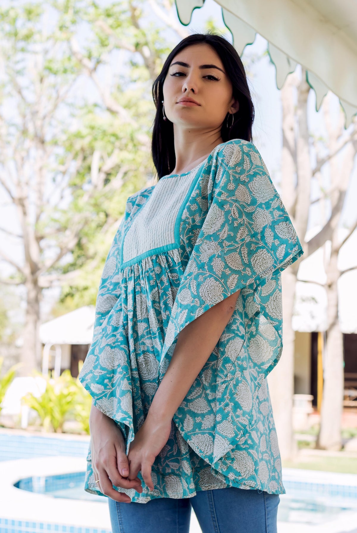 Model wearing a flowing sea blue kaftan top with white hand-block-printed floral patterns.