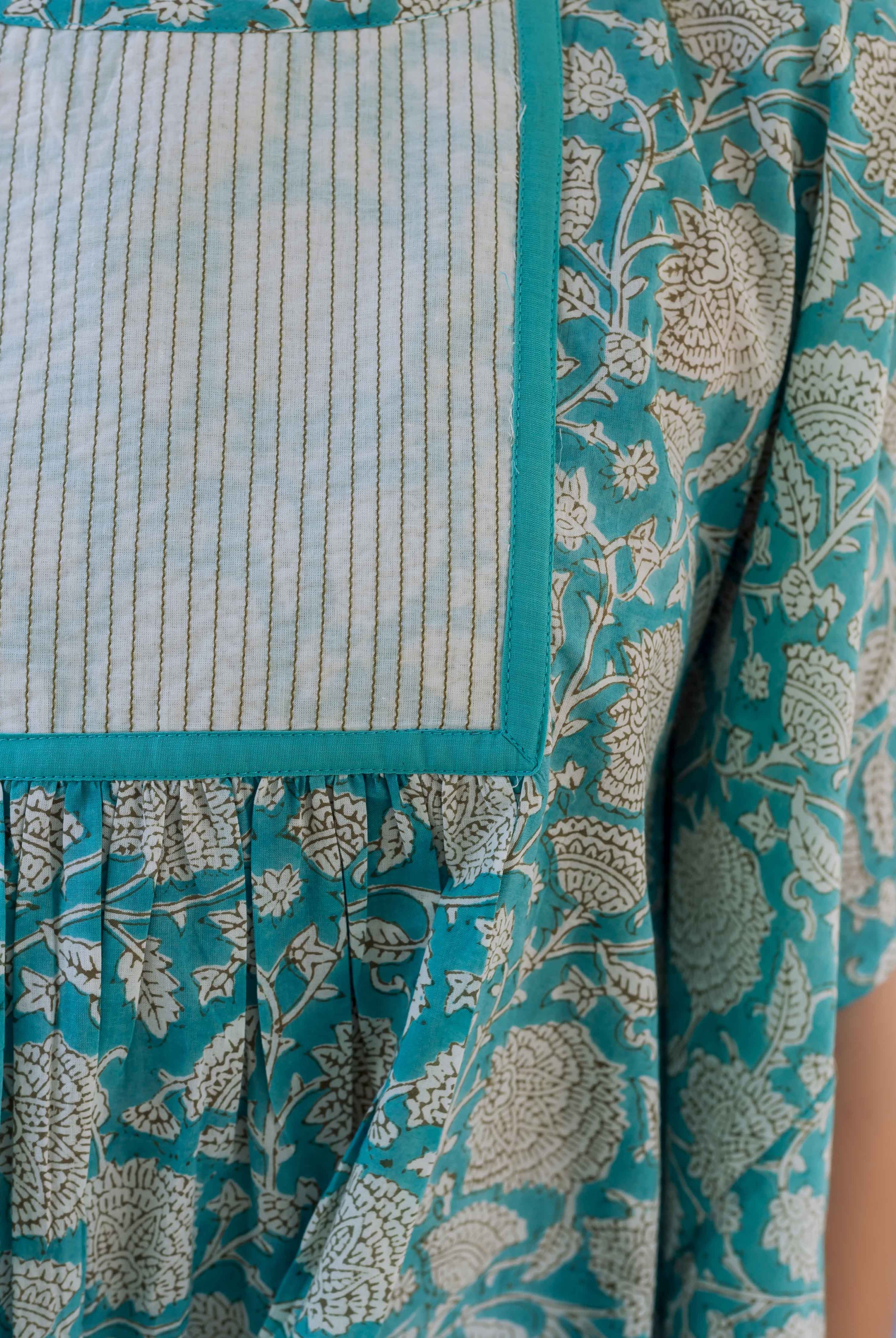 Close-up of a sea blue floral kaftan top with a striped yoke and gathered fabric.