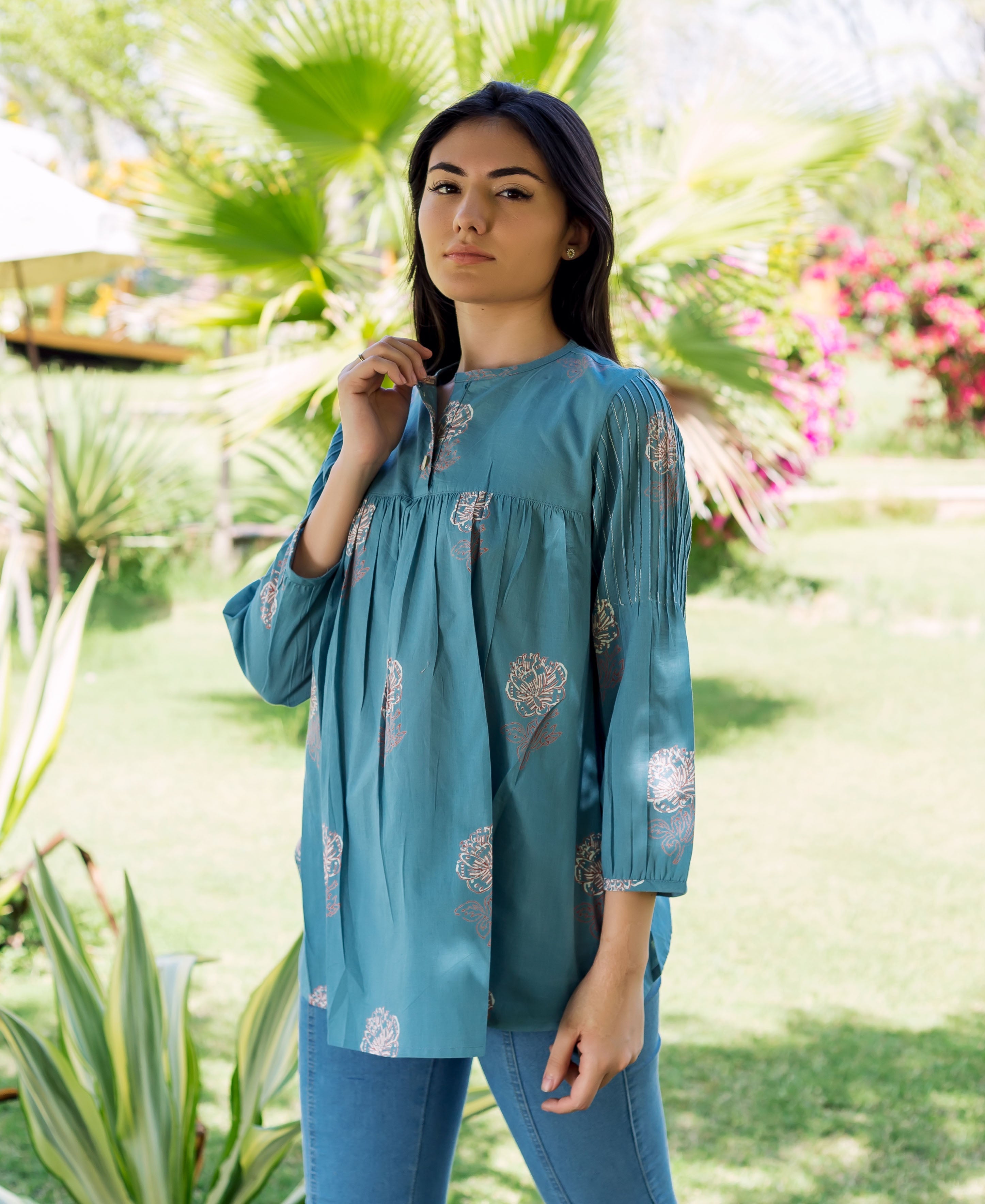 Woman wearing a stone blue hand-block-printed top with floral print and pleated statement sleeves.