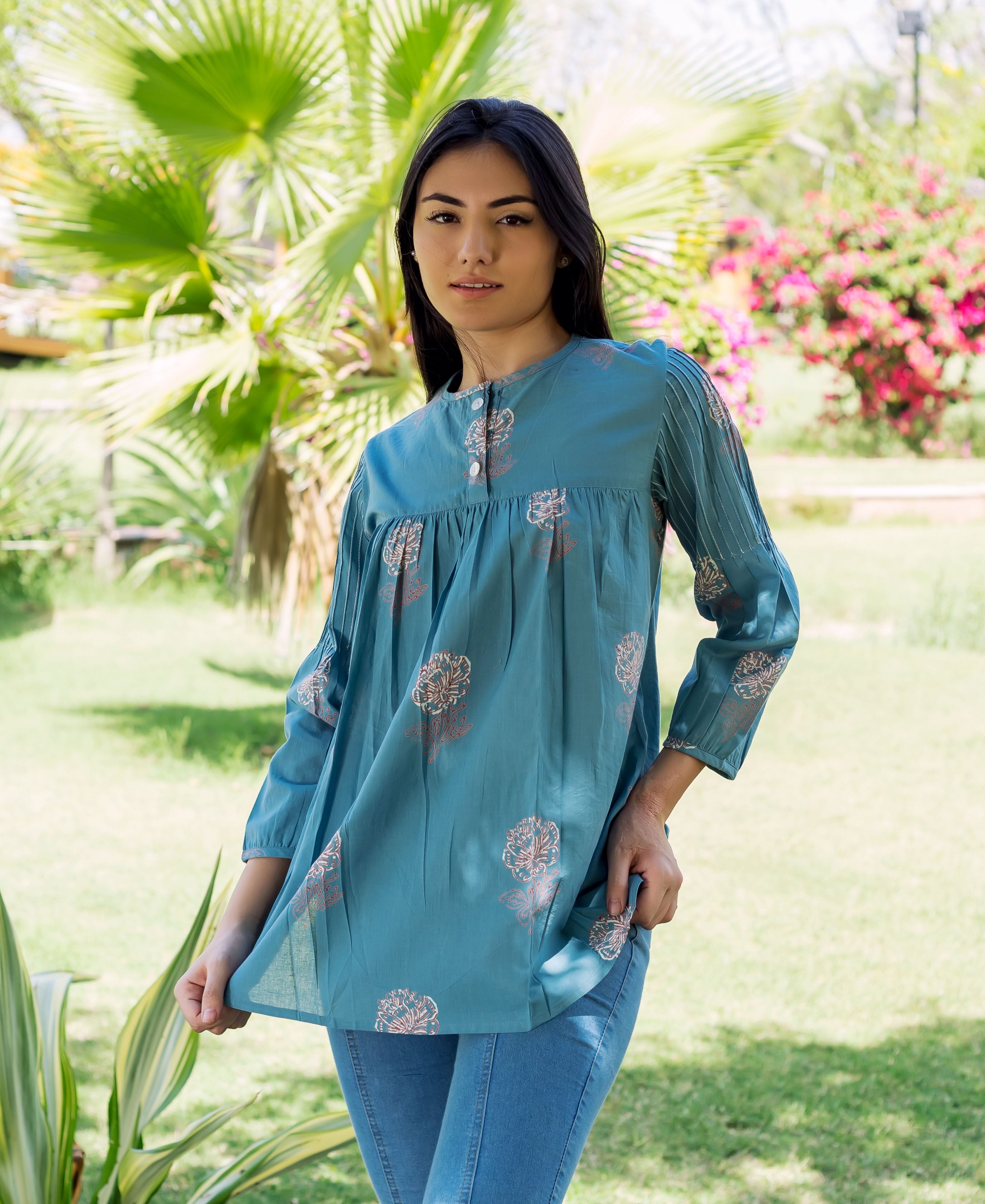 Model in a stone blue top, hand-block-printed with floral patterns and pleated sleeves.