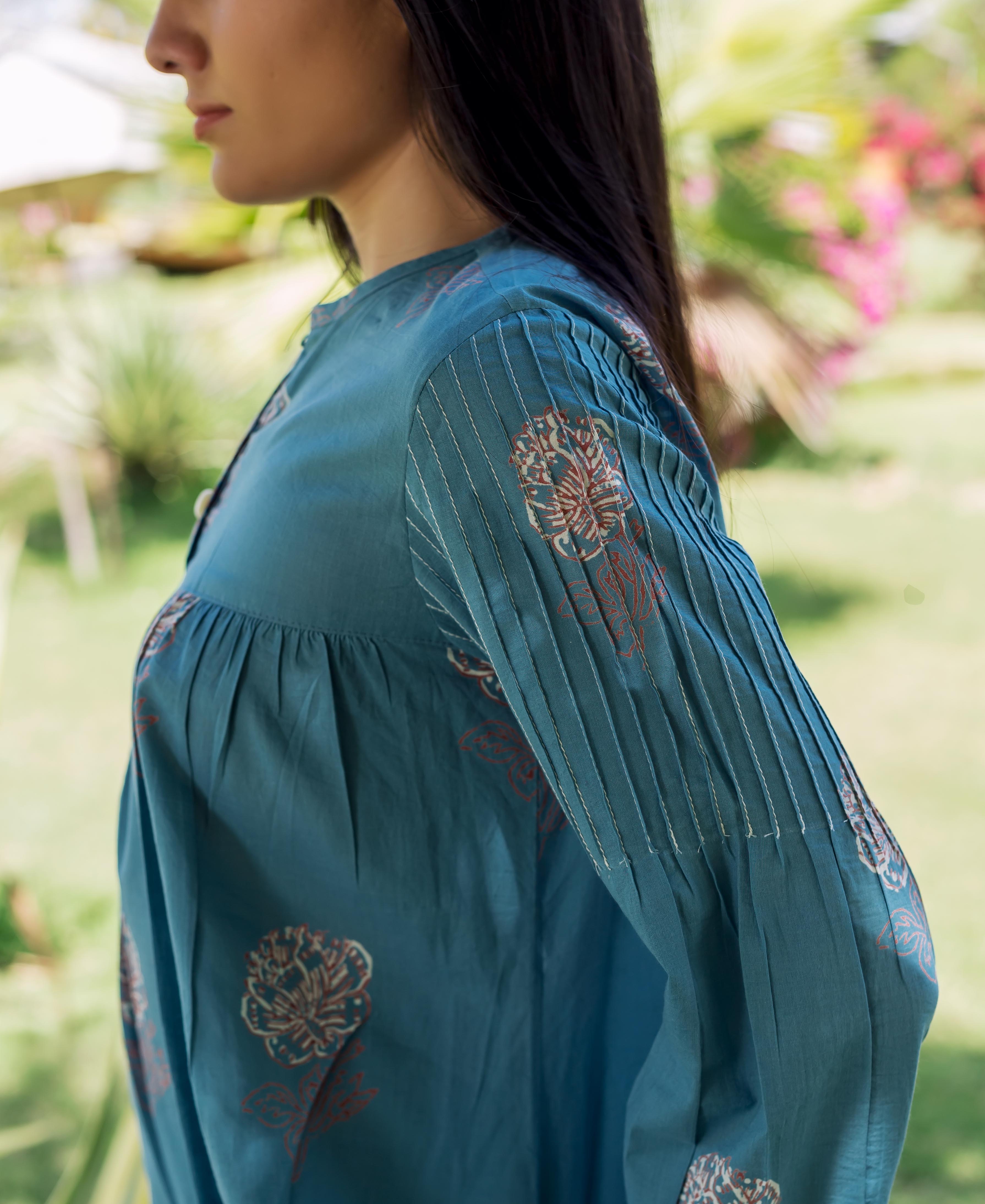 Side-profile of model wearing a stone blue printed top with pleated statement sleeves.