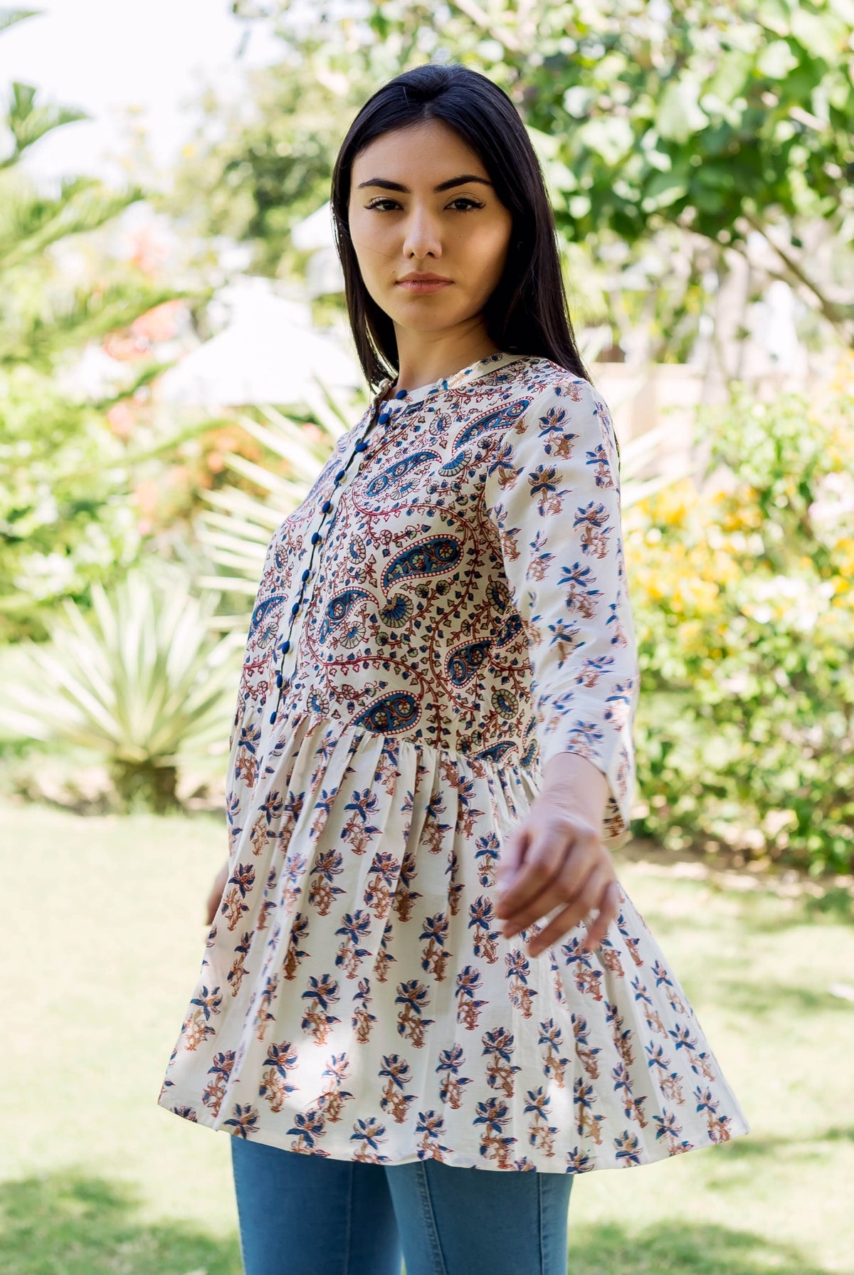 Model wears a white ethnic hand-block-printed peplum top with brown and blue floral print.