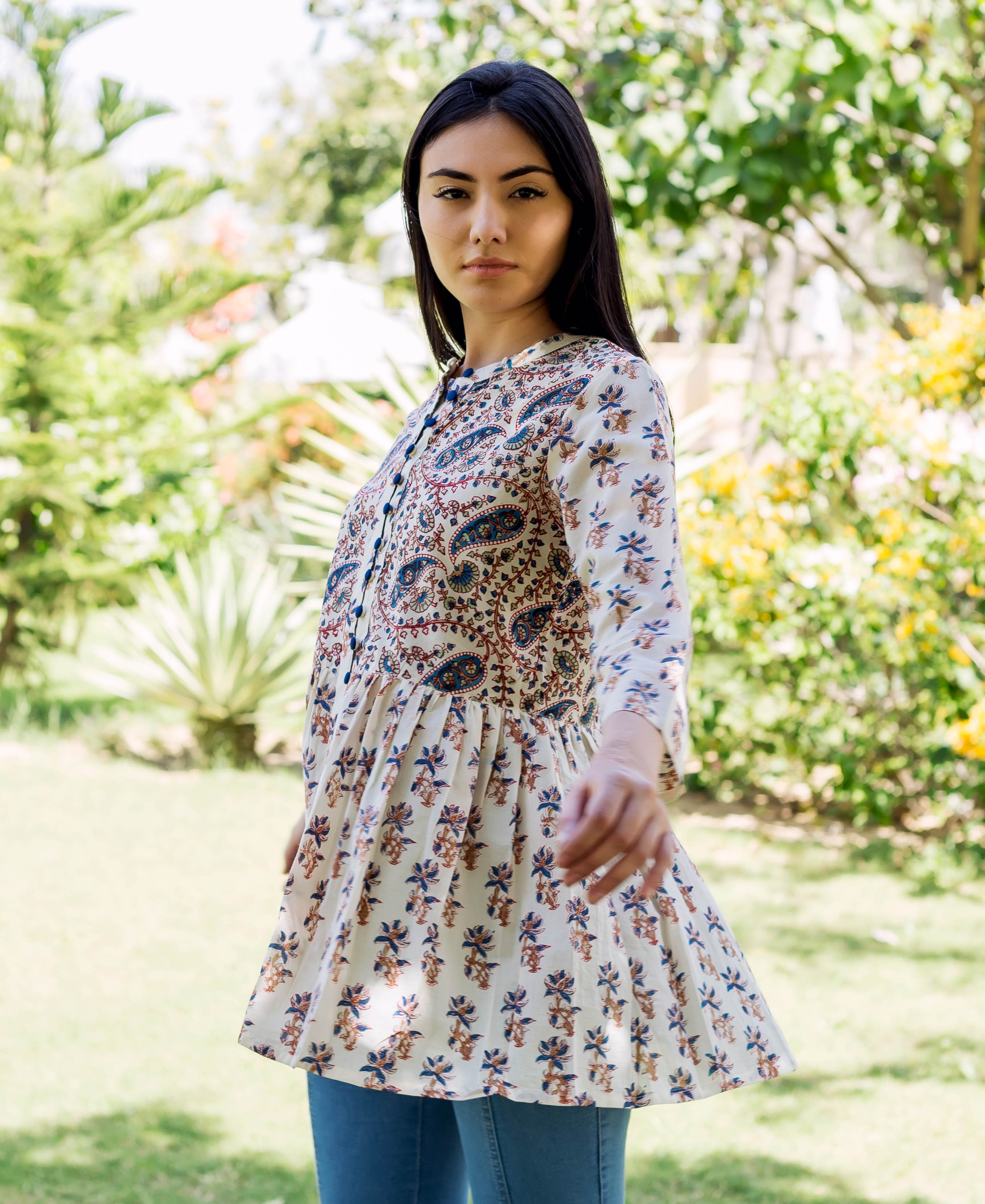 Model wears a white ethnic hand-block-printed peplum top with brown and blue floral print.