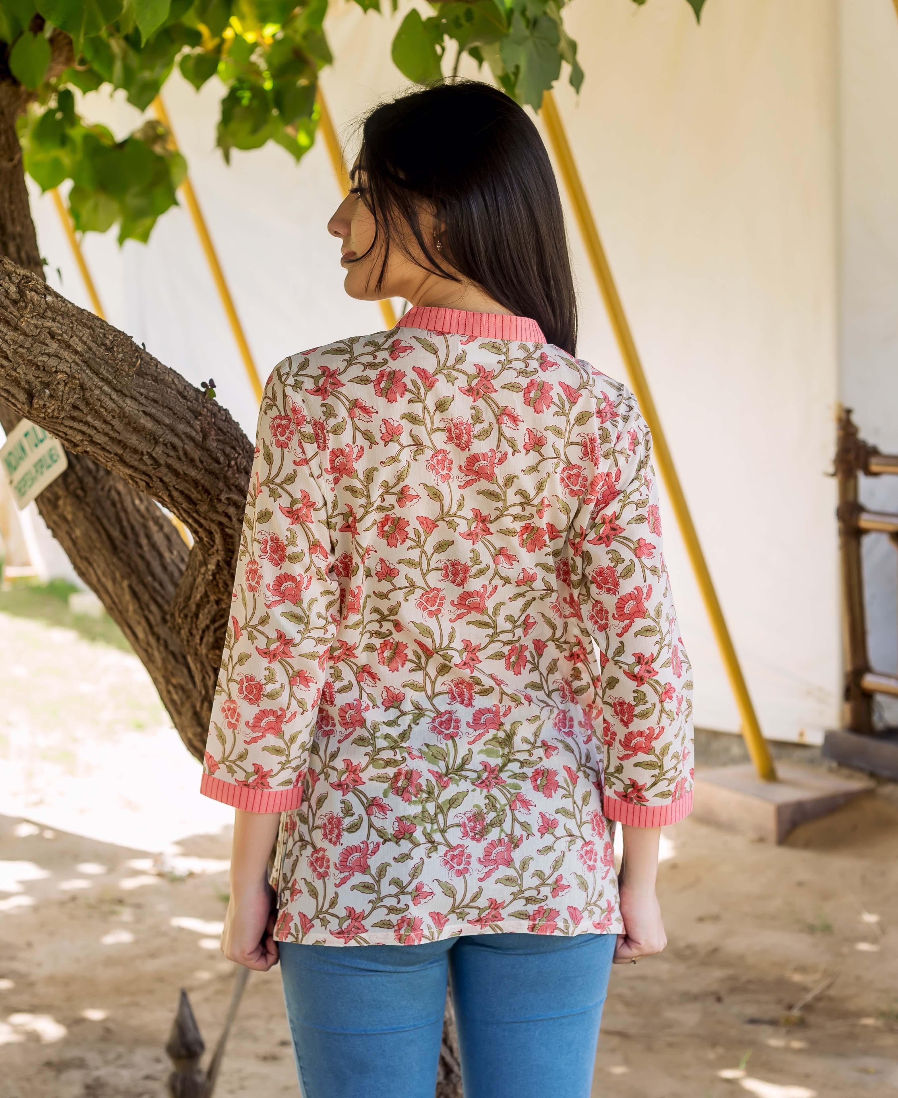 Back view of model in a peach floral printed top with pink collar and cuffs.