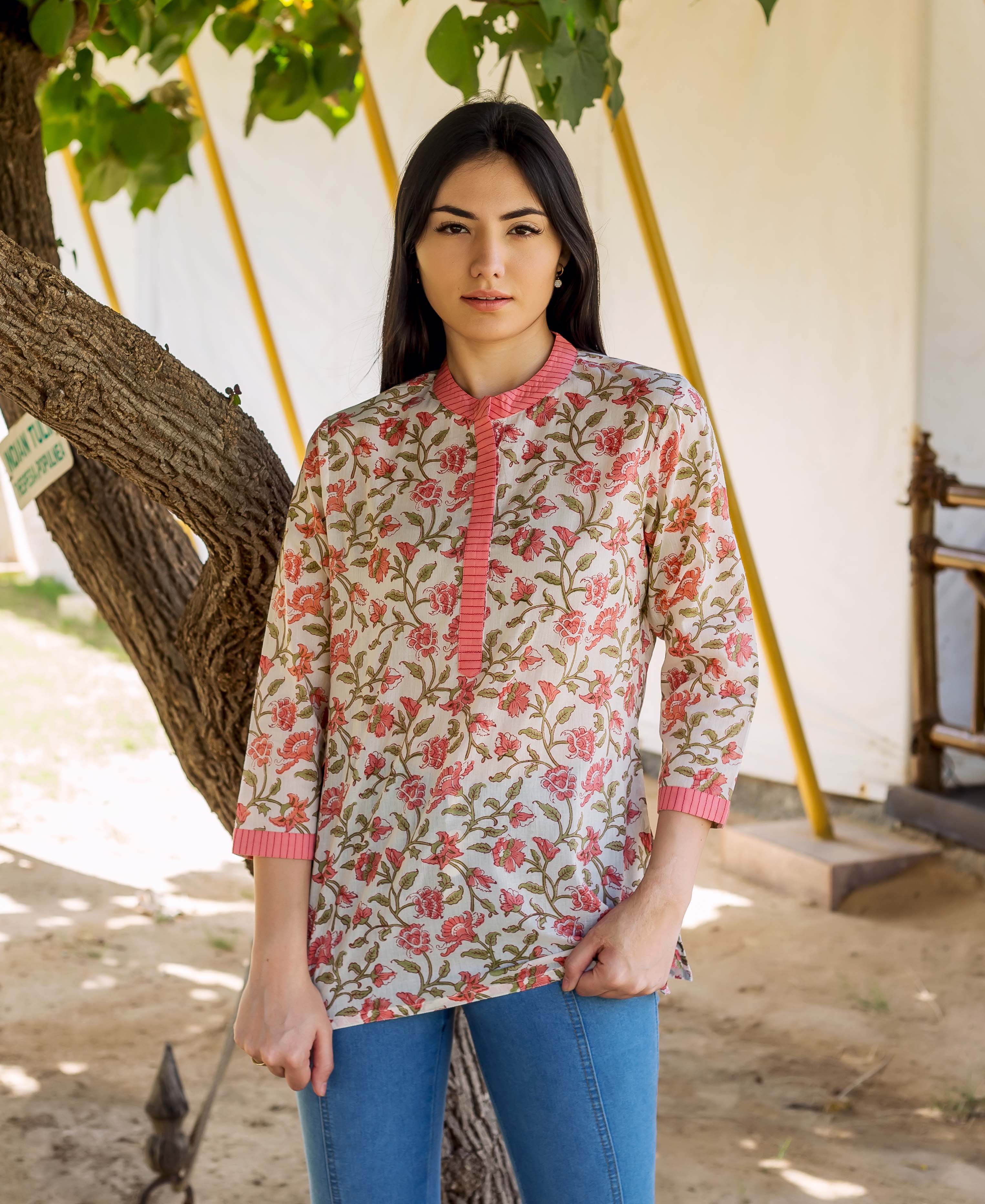 Model in a cream top with peach floral hand-block print and striped collar, blue jeans.