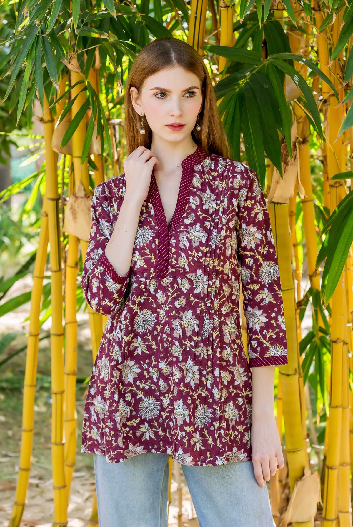 Model wears a wine hand-block-printed top with white and yellow floral patterns.