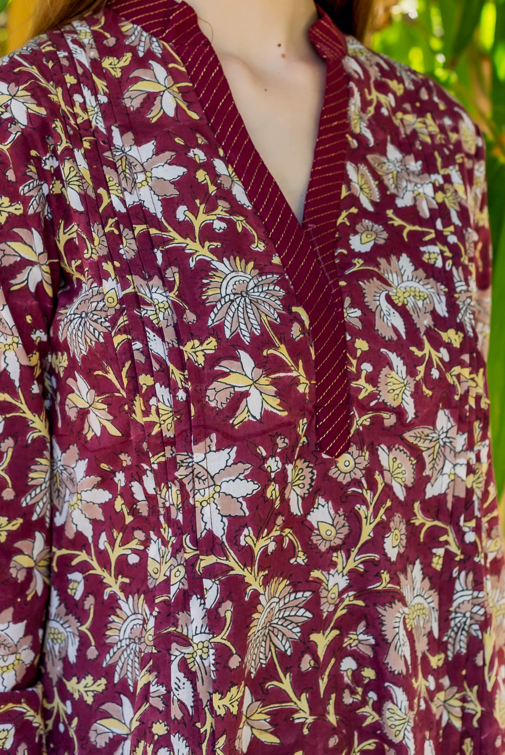 Close-up of a model wearing a wine-colored hand-block printed floral top with a V-neck and pleats.
