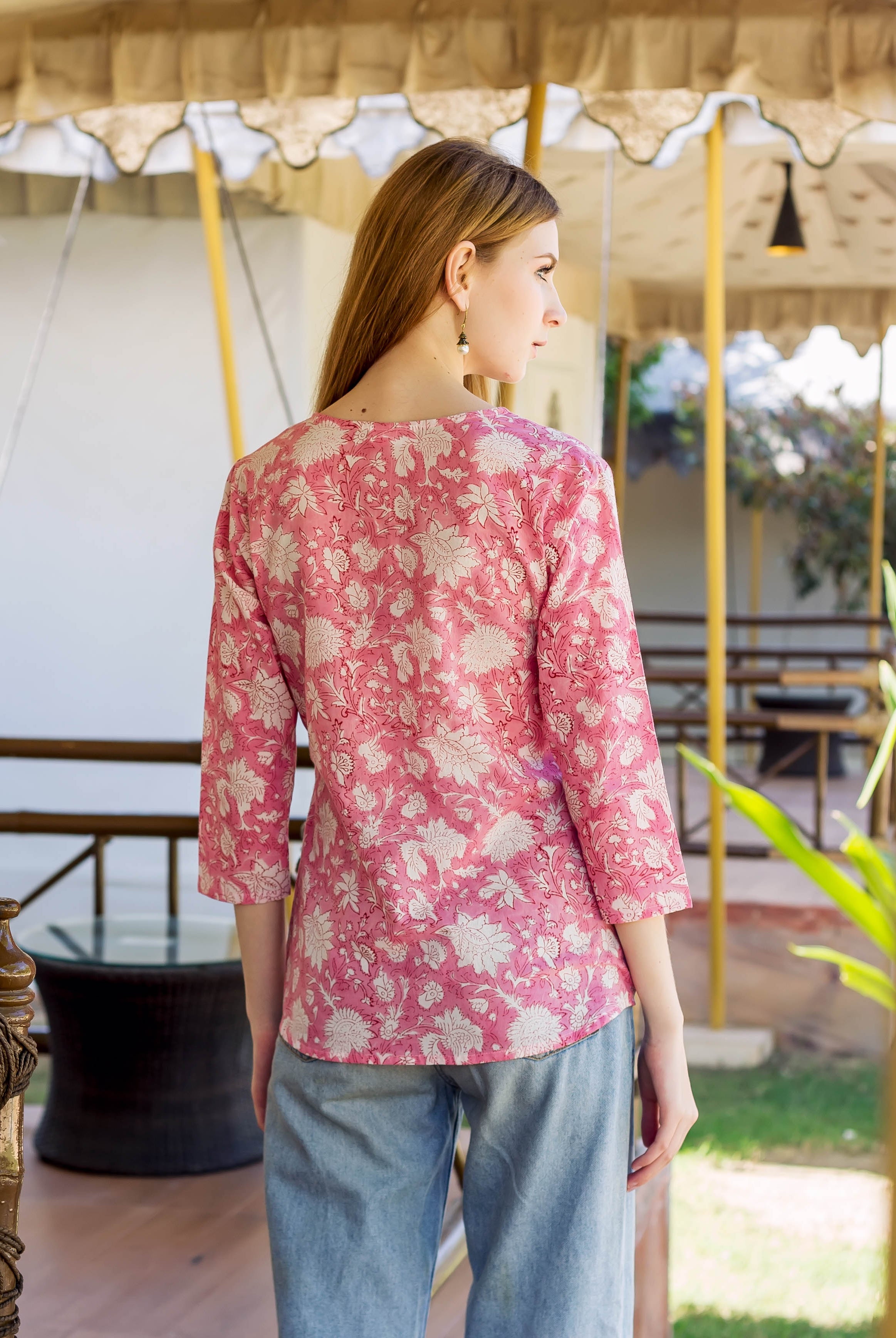Back view of model wearing a pink top with white floral print and 3/4 sleeves.