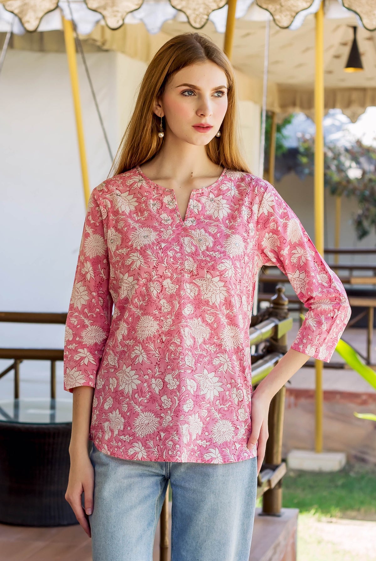 Model in a pink hand-block-printed floral tunic with V-neck and 3/4 sleeves.