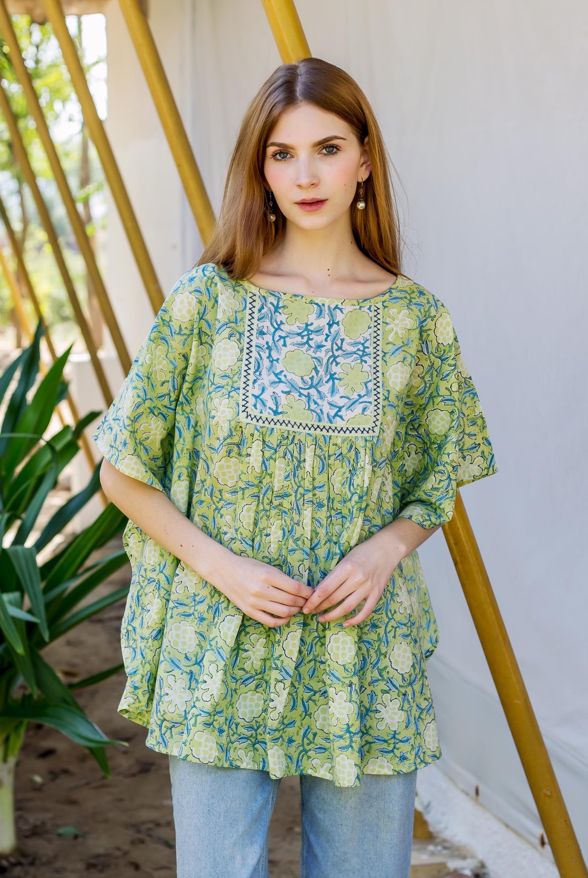 Front view of a model wearing a lime green hand block printed kaftan top with blue floral motifs.