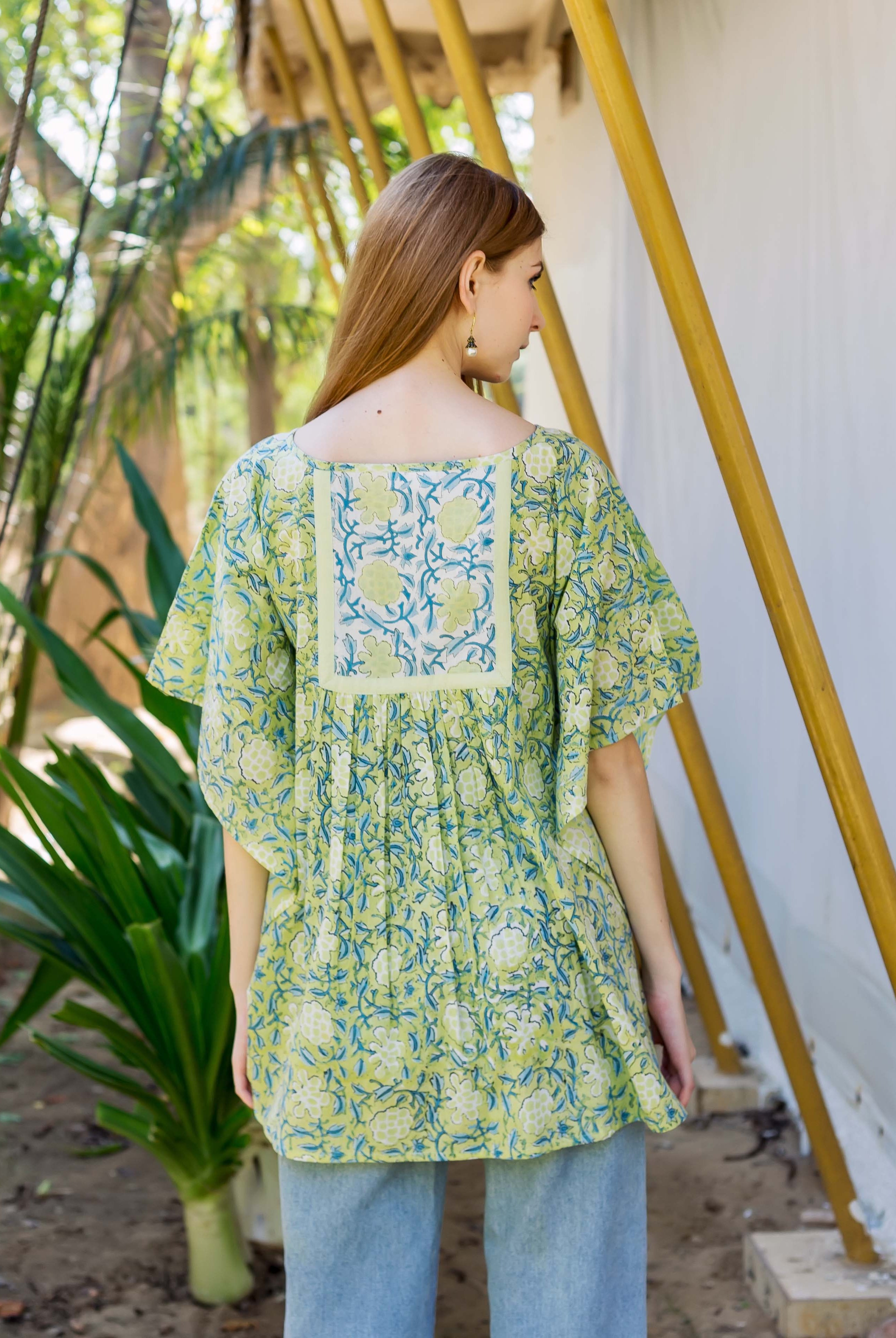 A model wearing a lime green kaftan top with a floral print.