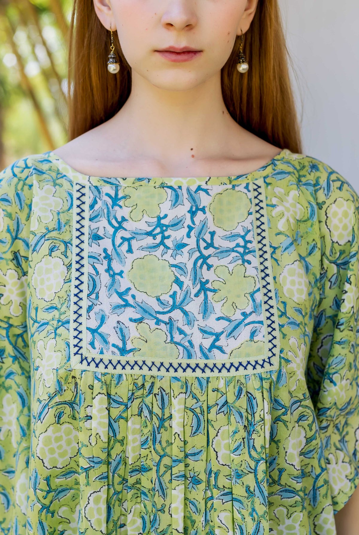 Model in lime green, blue, and white floral hand block printed kaftan top with pleated detail.