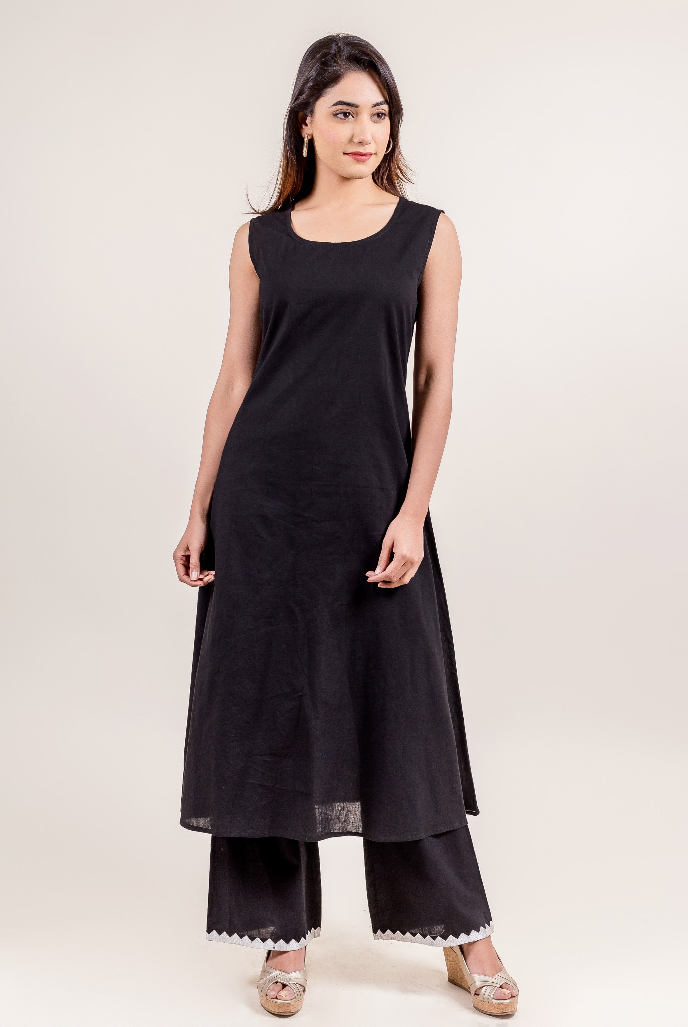 Front full look of model wearing a black sleeveless tunic and black zigzag palazzo pants.