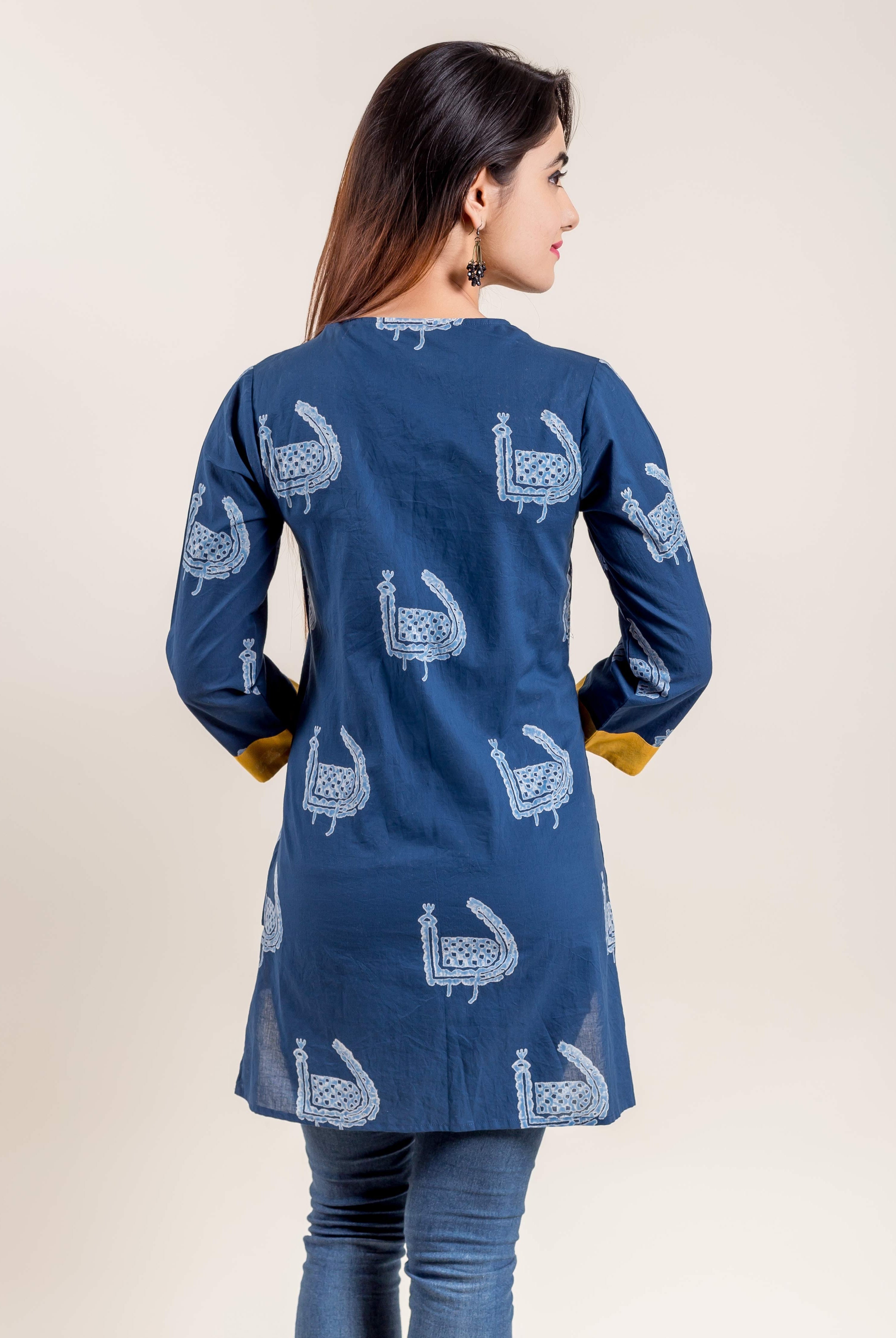 Model from back wearing indigo short kurti with white block print and yellow cuffs.