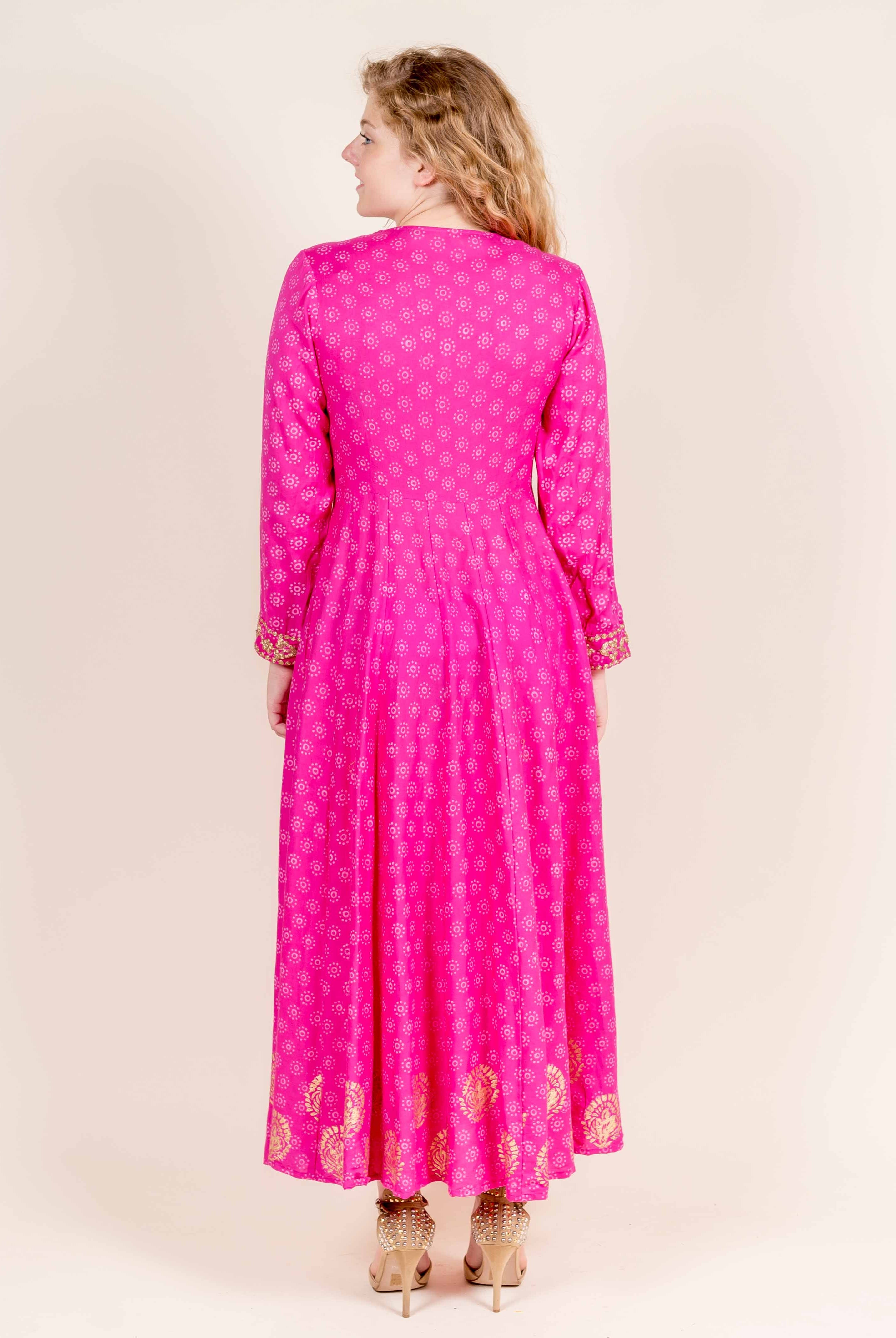 Back view of a model in a fuchsia flared full-sleeves dress with golden hand block prints.