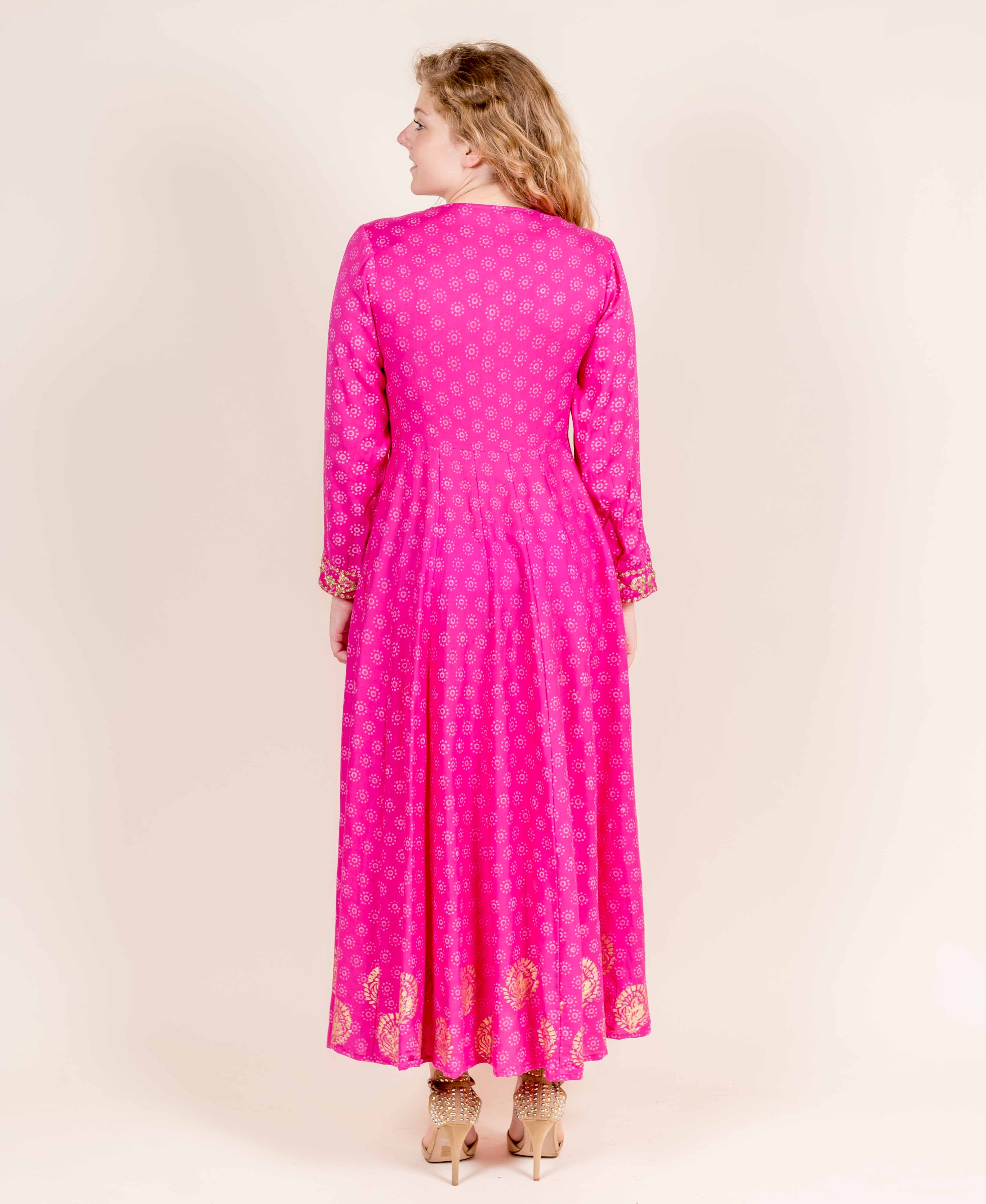 Back view of a model in a fuchsia flared full-sleeves dress with golden hand block prints.