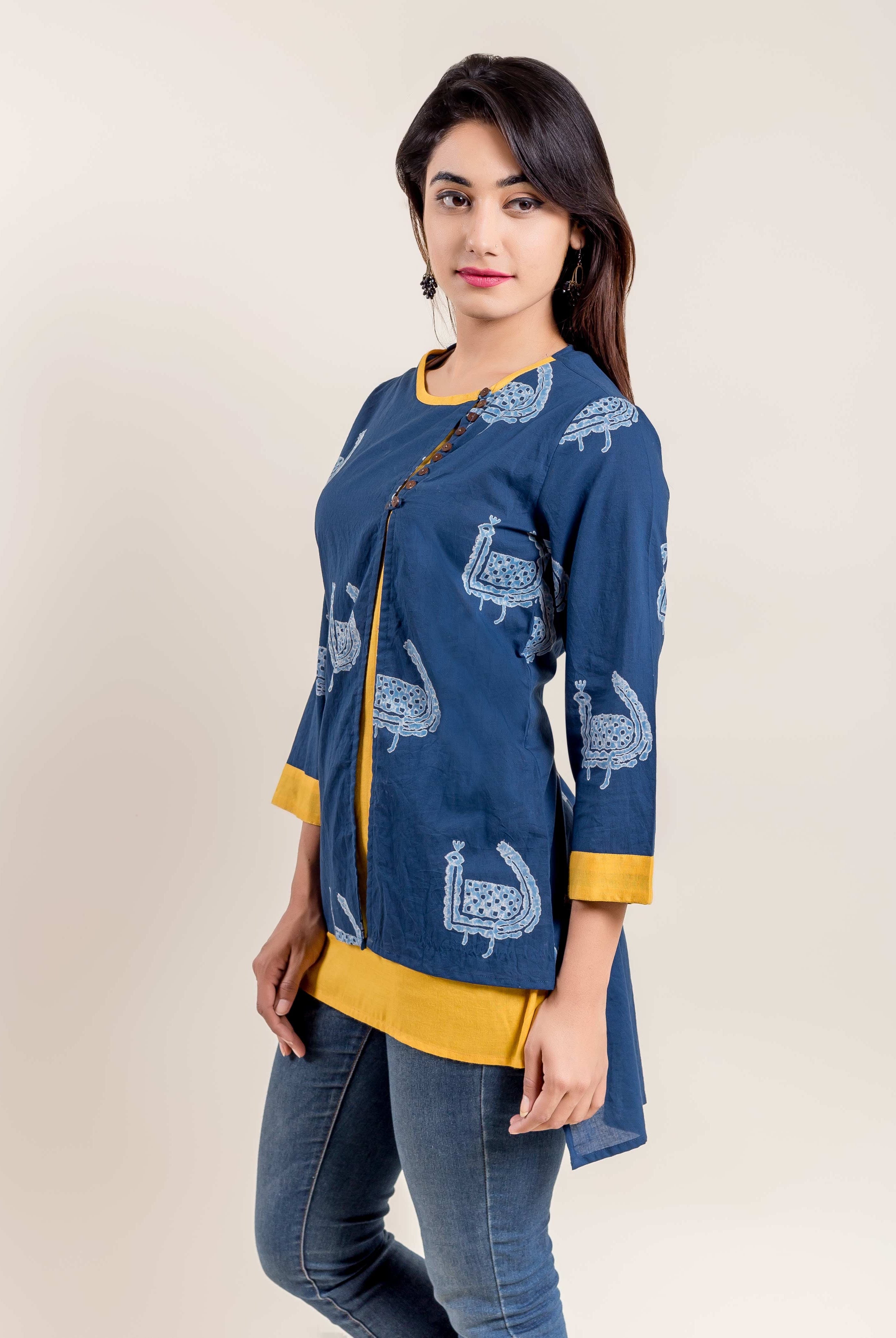 Woman in indigo blue kurti with white ethnic bird print, yellow layered hem, and side buttons.