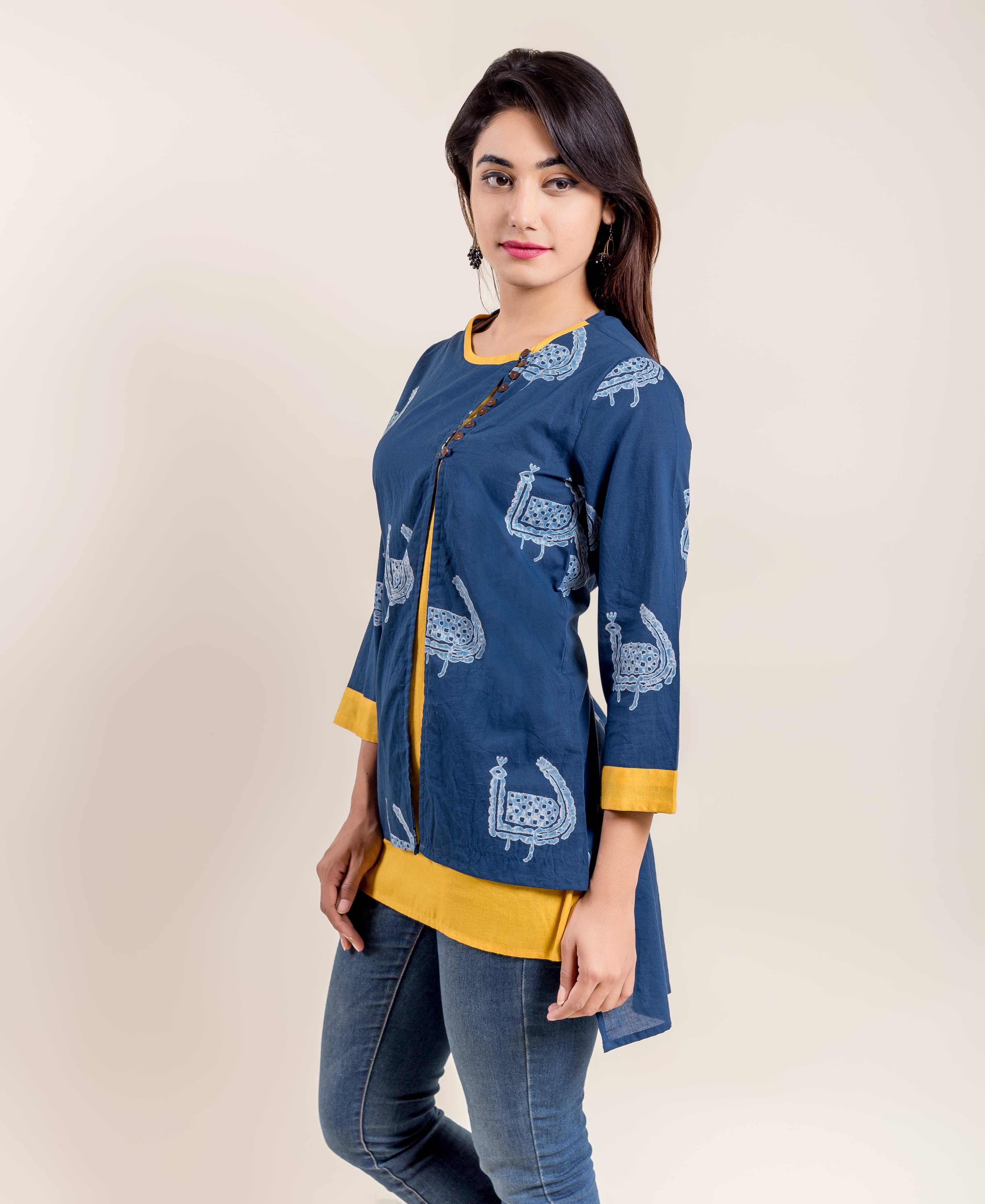 Woman in indigo blue kurti with white ethnic bird print, yellow layered hem, and side buttons.