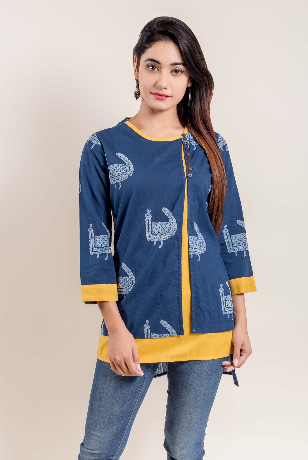 Front view of woman in indigo yellow double-layered side-buttoned printed ethnic short kurti.