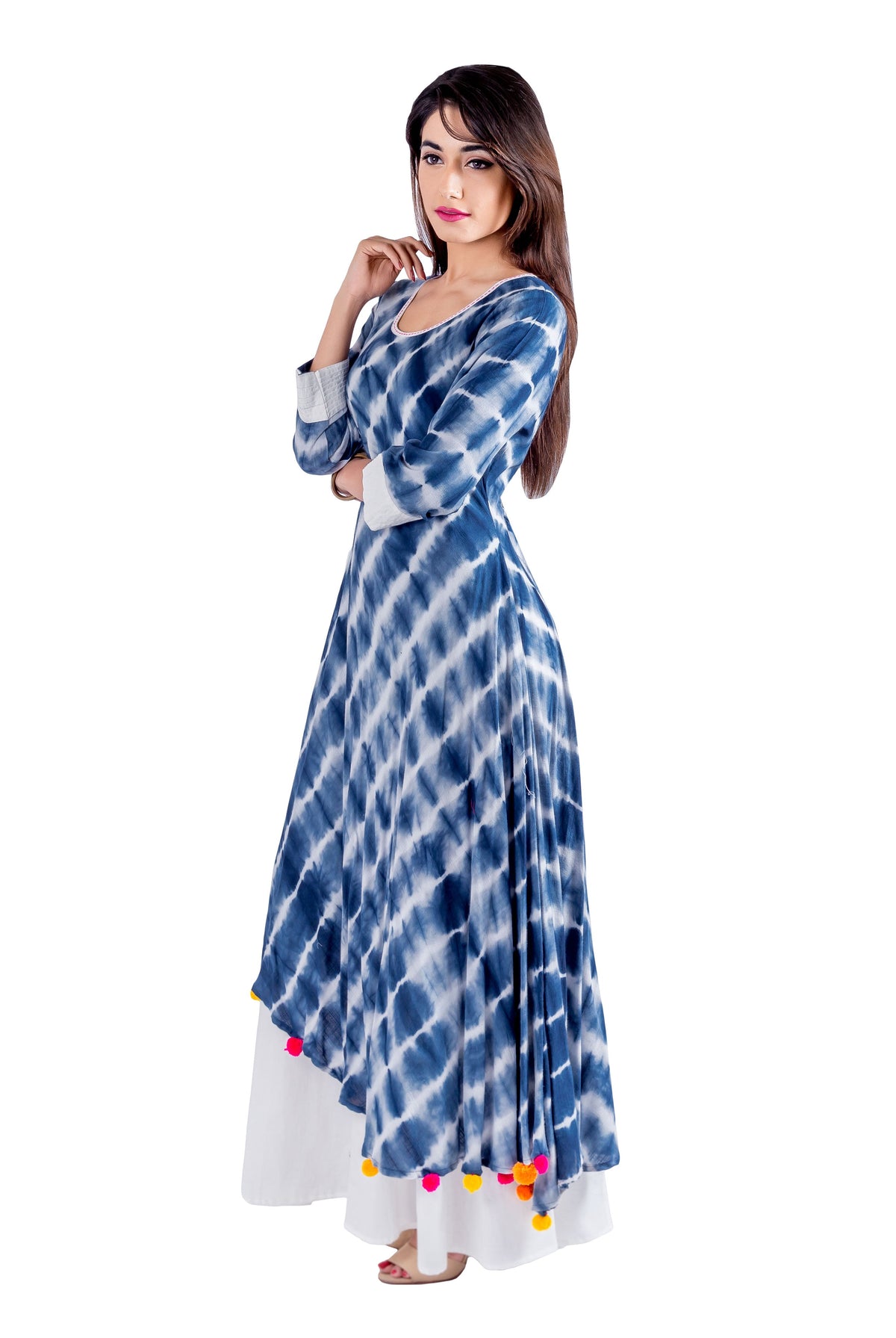 Model wears a blue and white tie-dye asymmetrical kurti dress with colorful pom-poms.