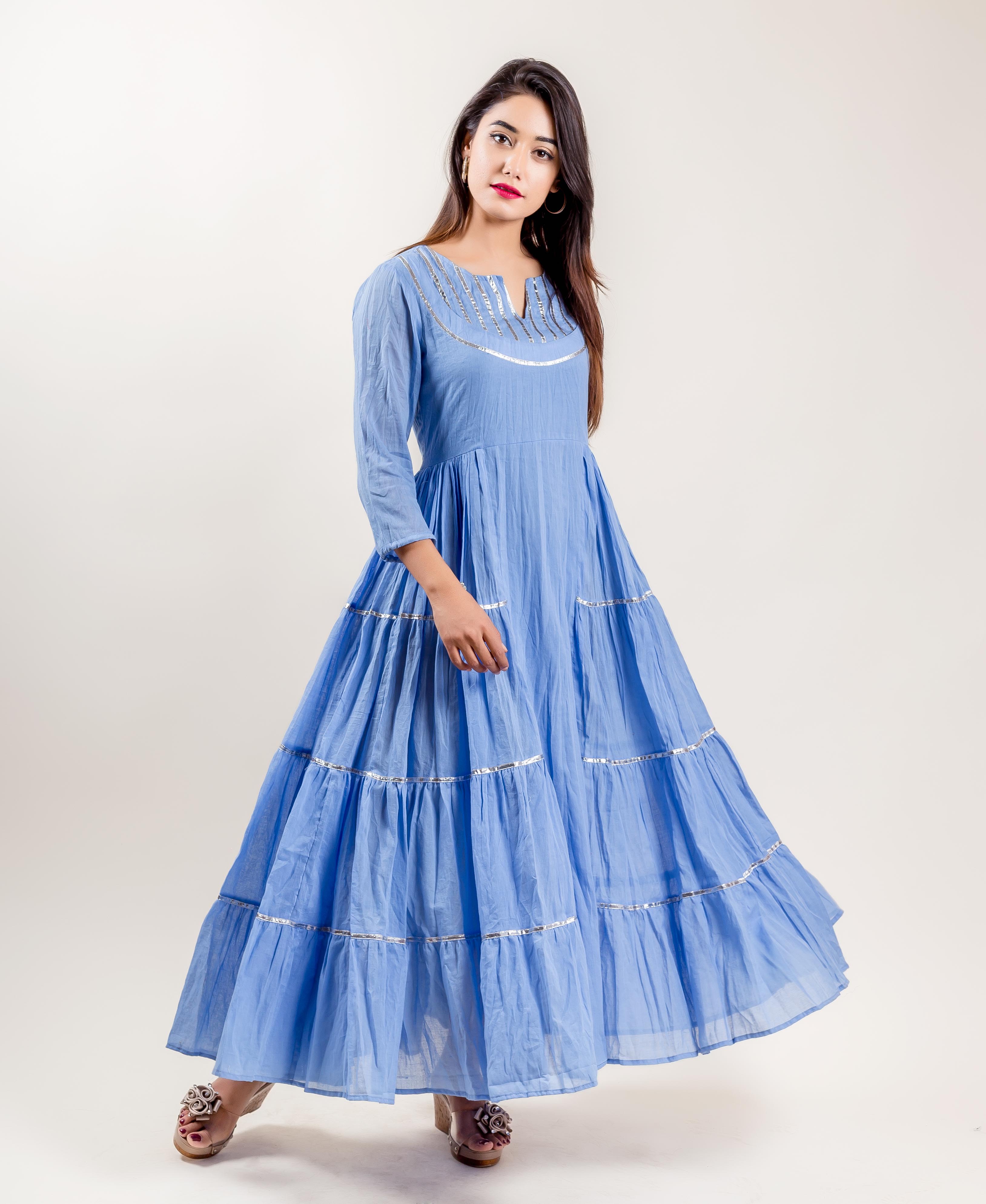 Full length front view of model in blue cotton tiered Indo-Western gown with silver trim.