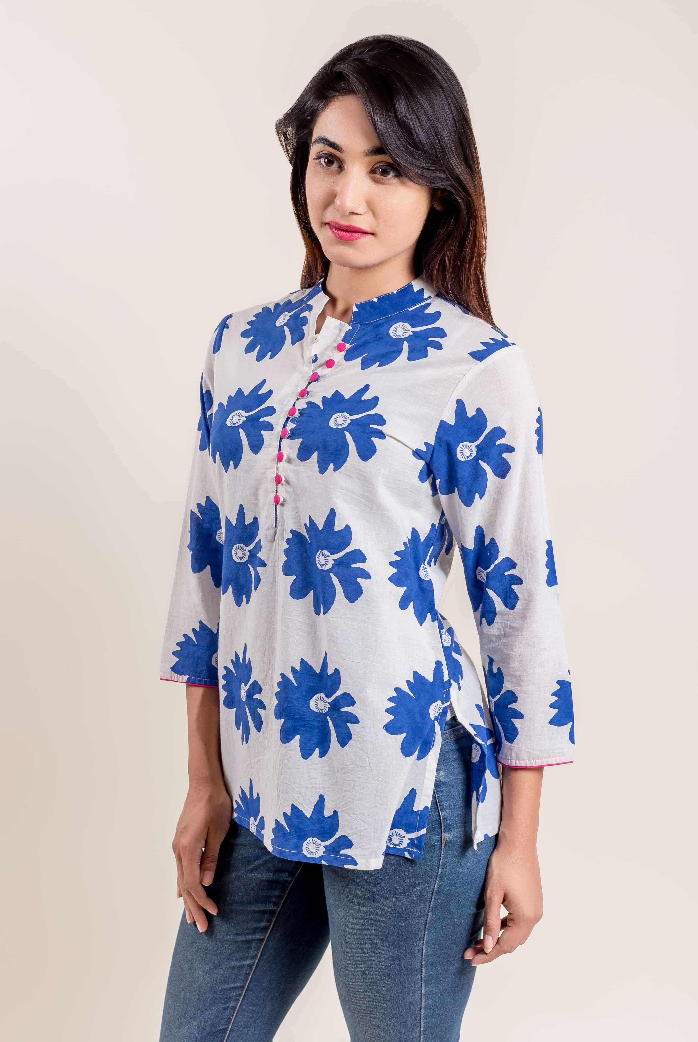 Model wears white blue floral hand block printed short kurti, mandarin collar, pink buttons.