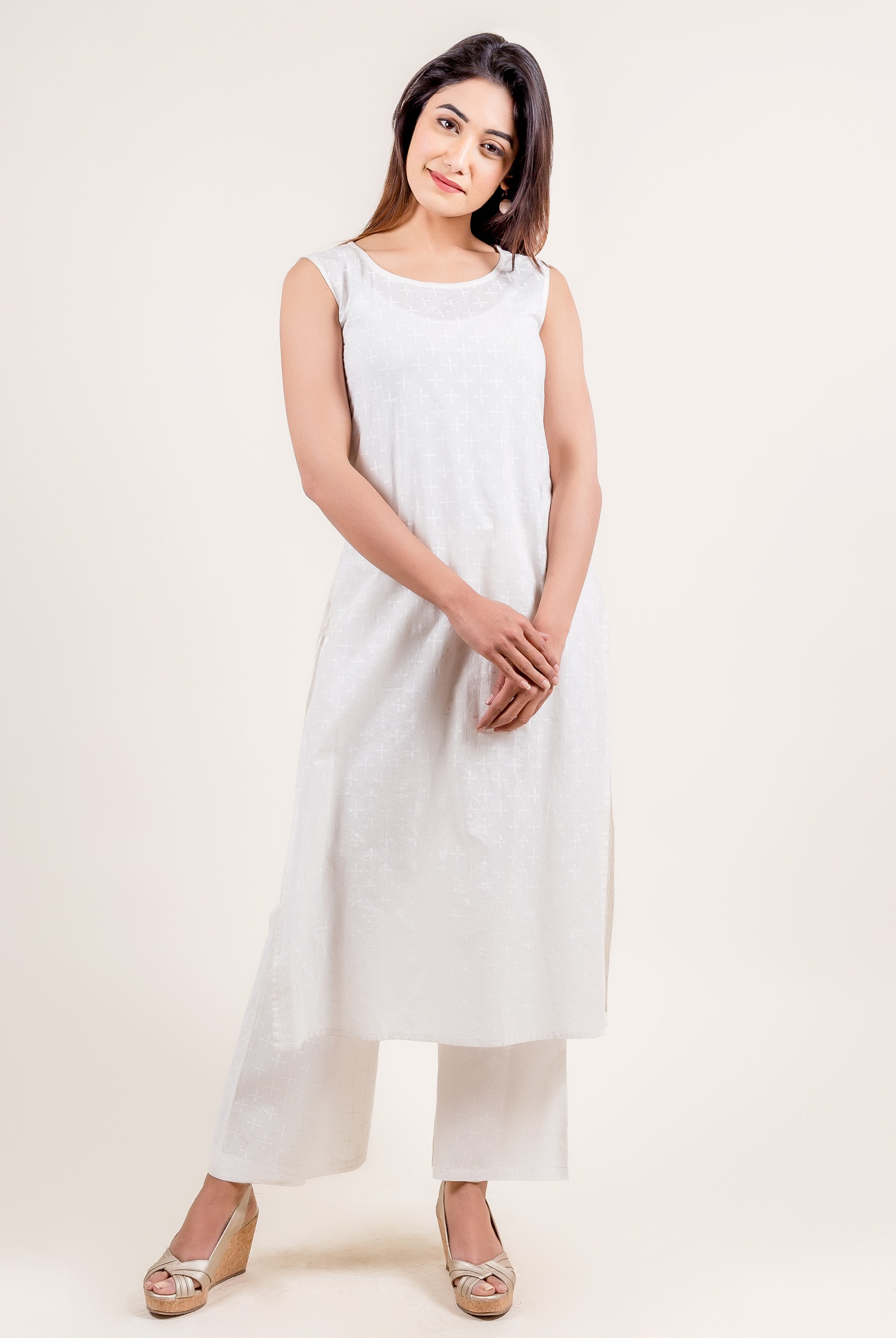 Full front view of model in white sleeveless kurta and wide-leg pants with subtle cross pattern.