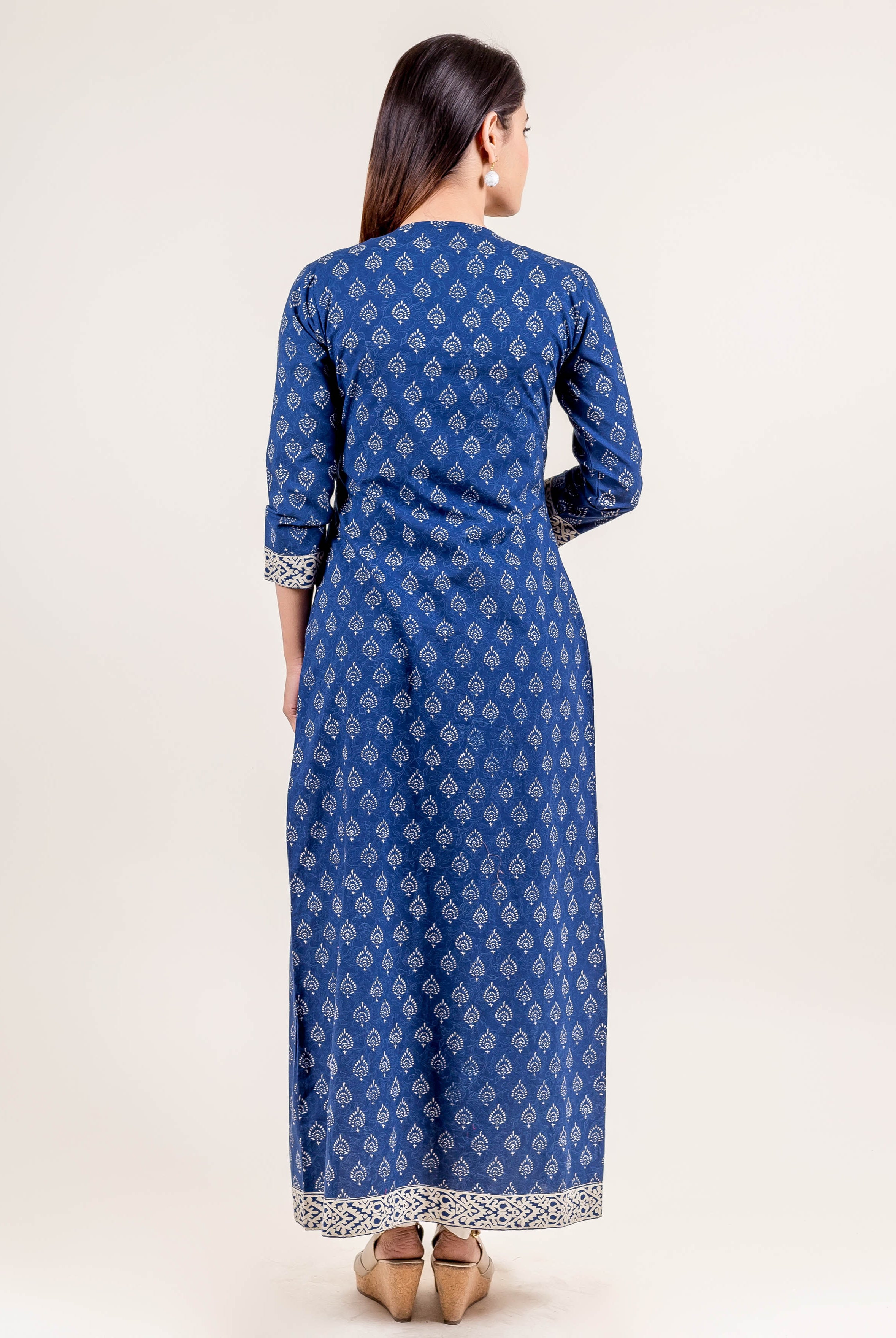 Back view of model in blue full-length dress with white hand block print patterns.