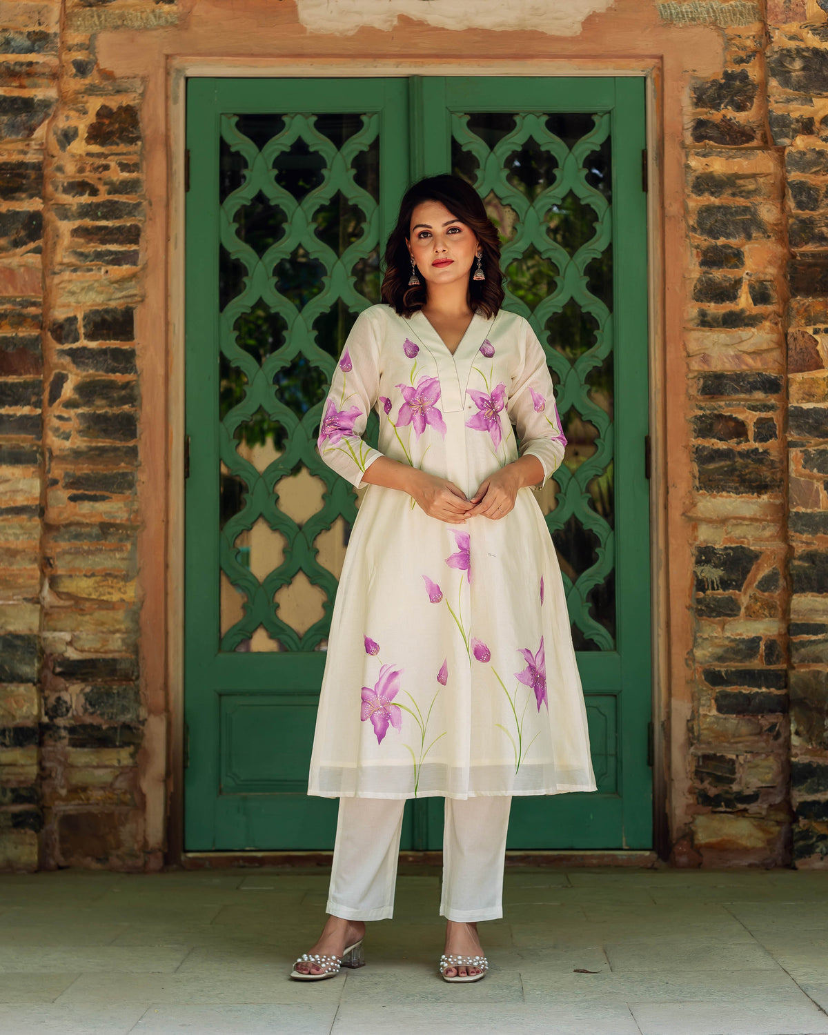Full-length shot of model wearing an ivory Chanderi kurta with hand-painted purple lilies and white pants.