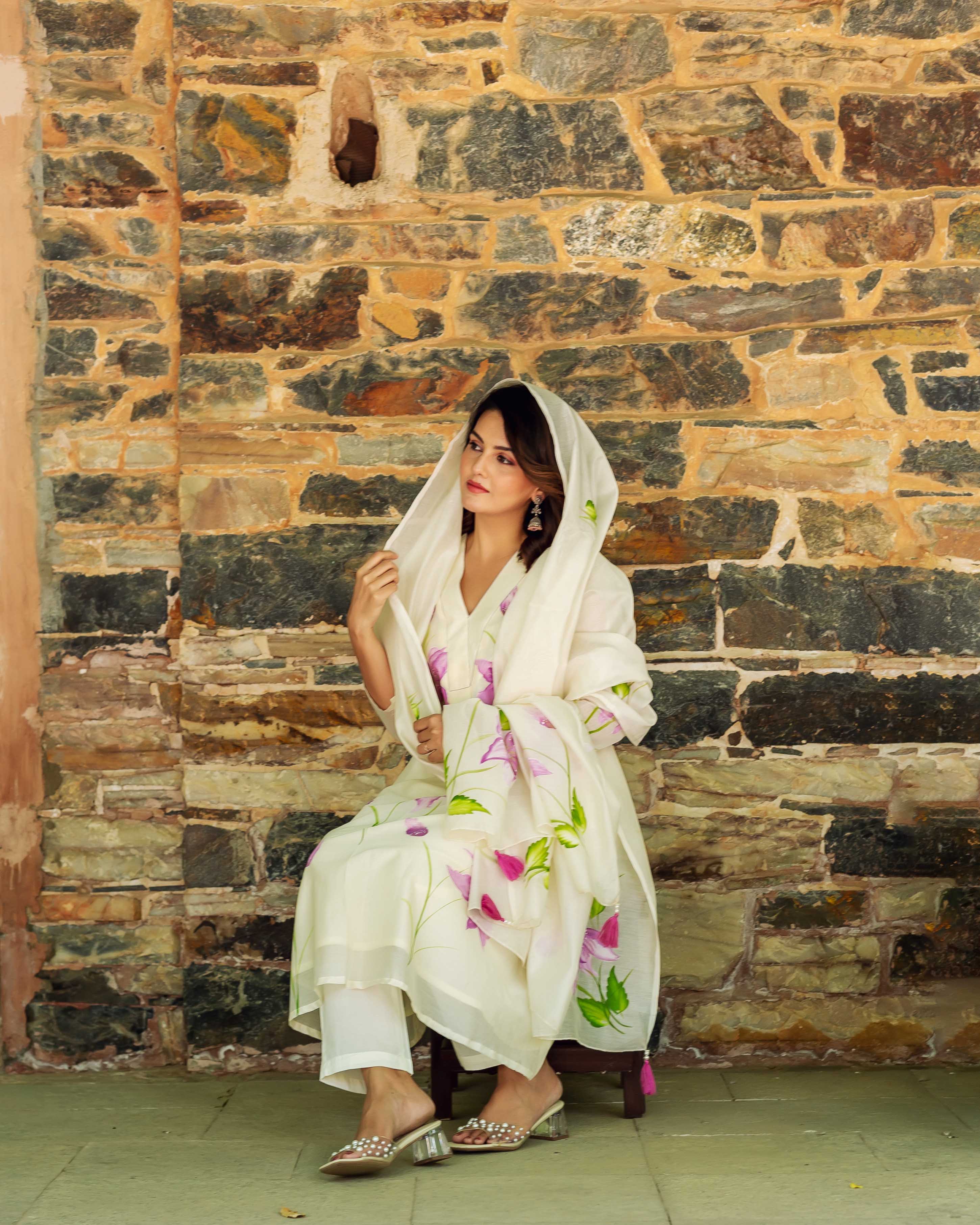 A woman in a white, hand-painted floral kurta with a matching dupatta.