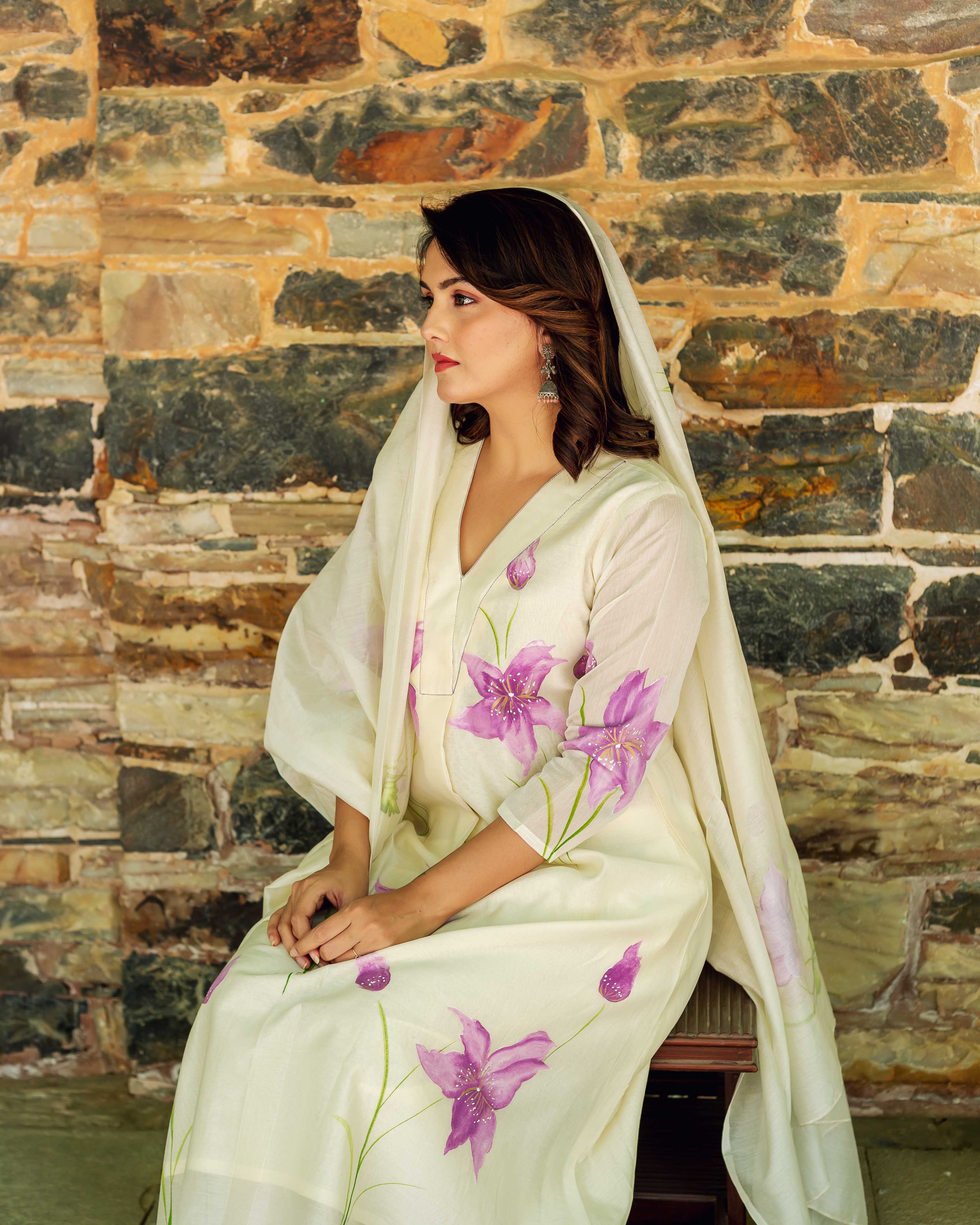 Side view of woman wearing ivory hand-painted chanderi kurta with large purple flowers.