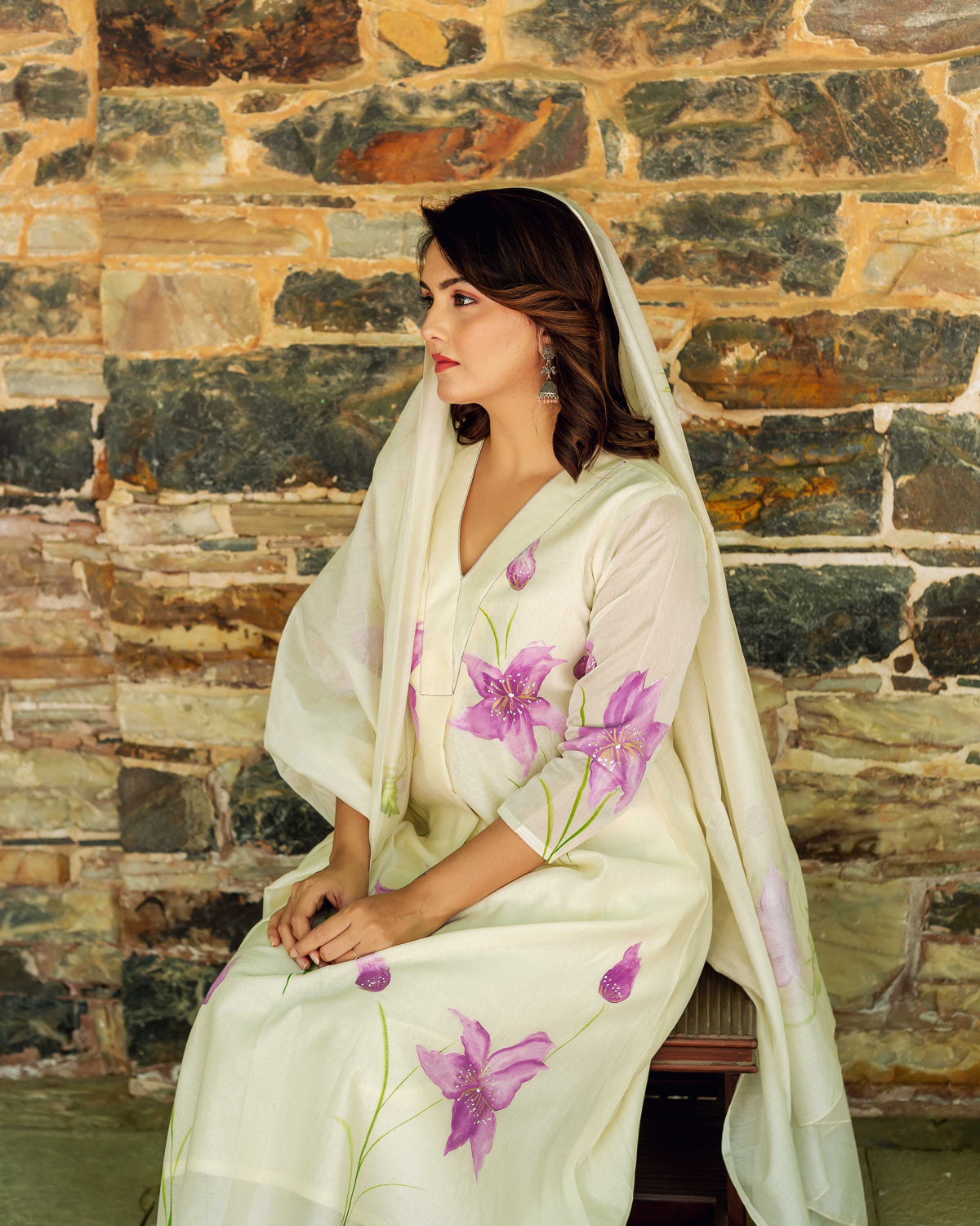 Side view of woman wearing ivory hand-painted chanderi kurta with large purple flowers.