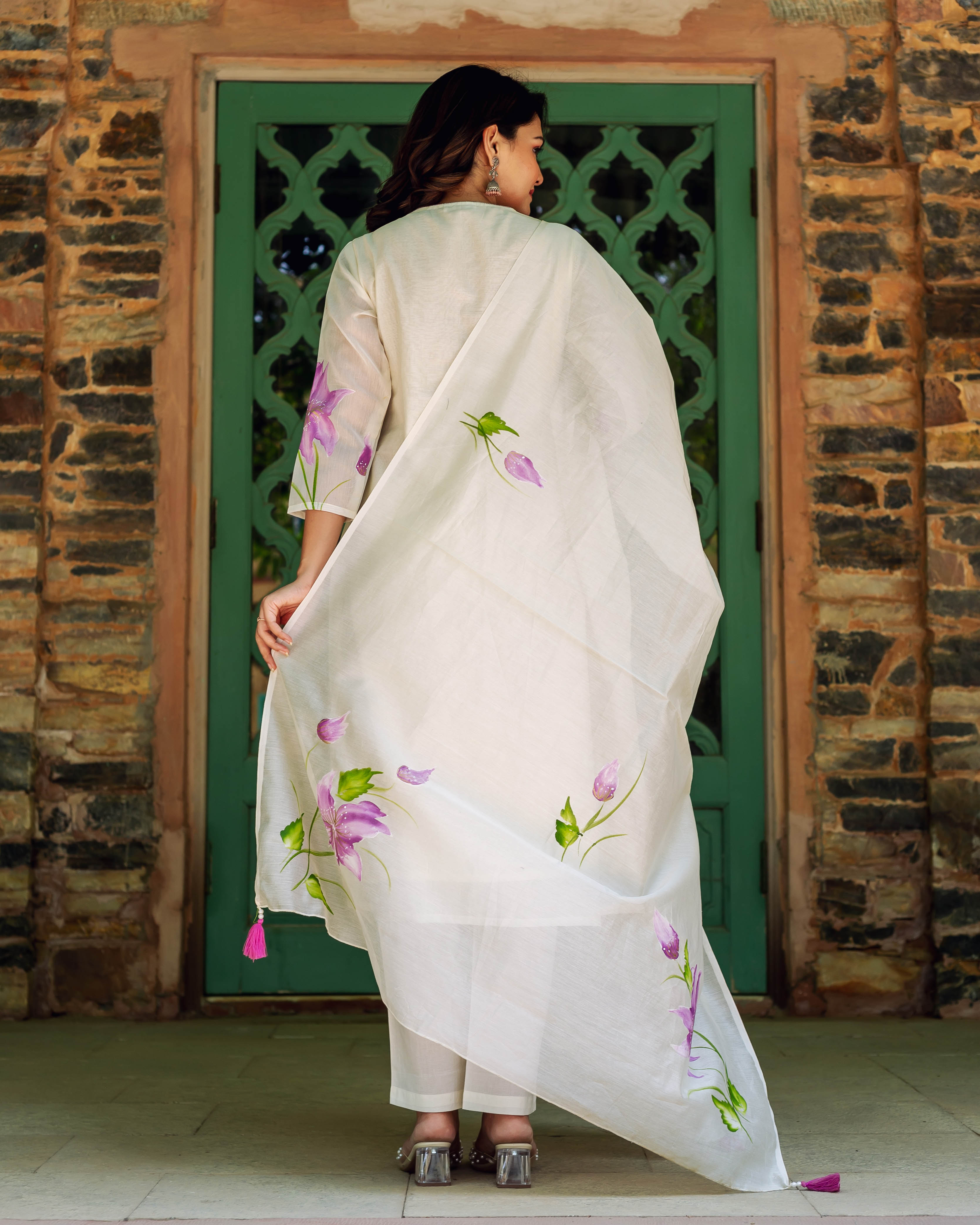 Woman in ivory hand-painted chanderi kurta set with purple blossoms, viewed from back.
