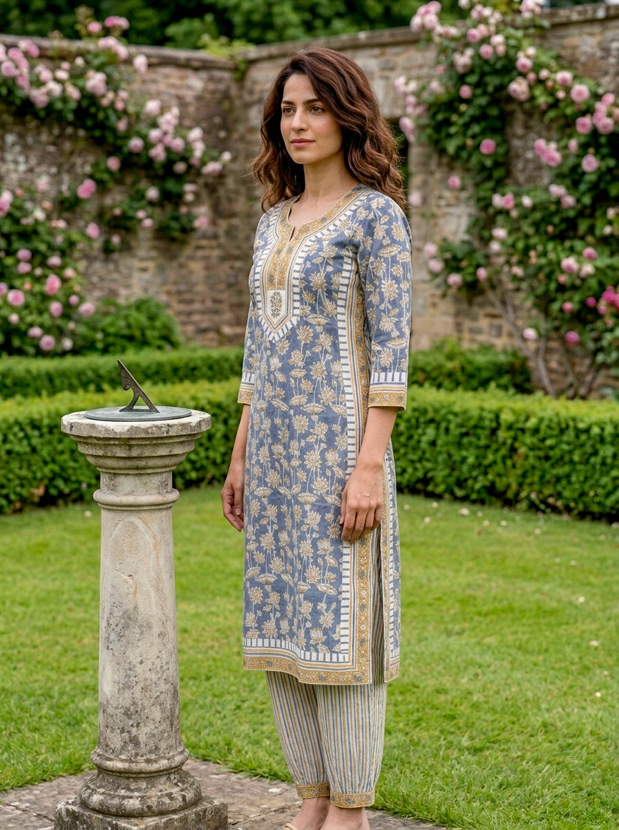 Model in dusty blue floral hand block print kurta set with striped Afghani salwar, side.