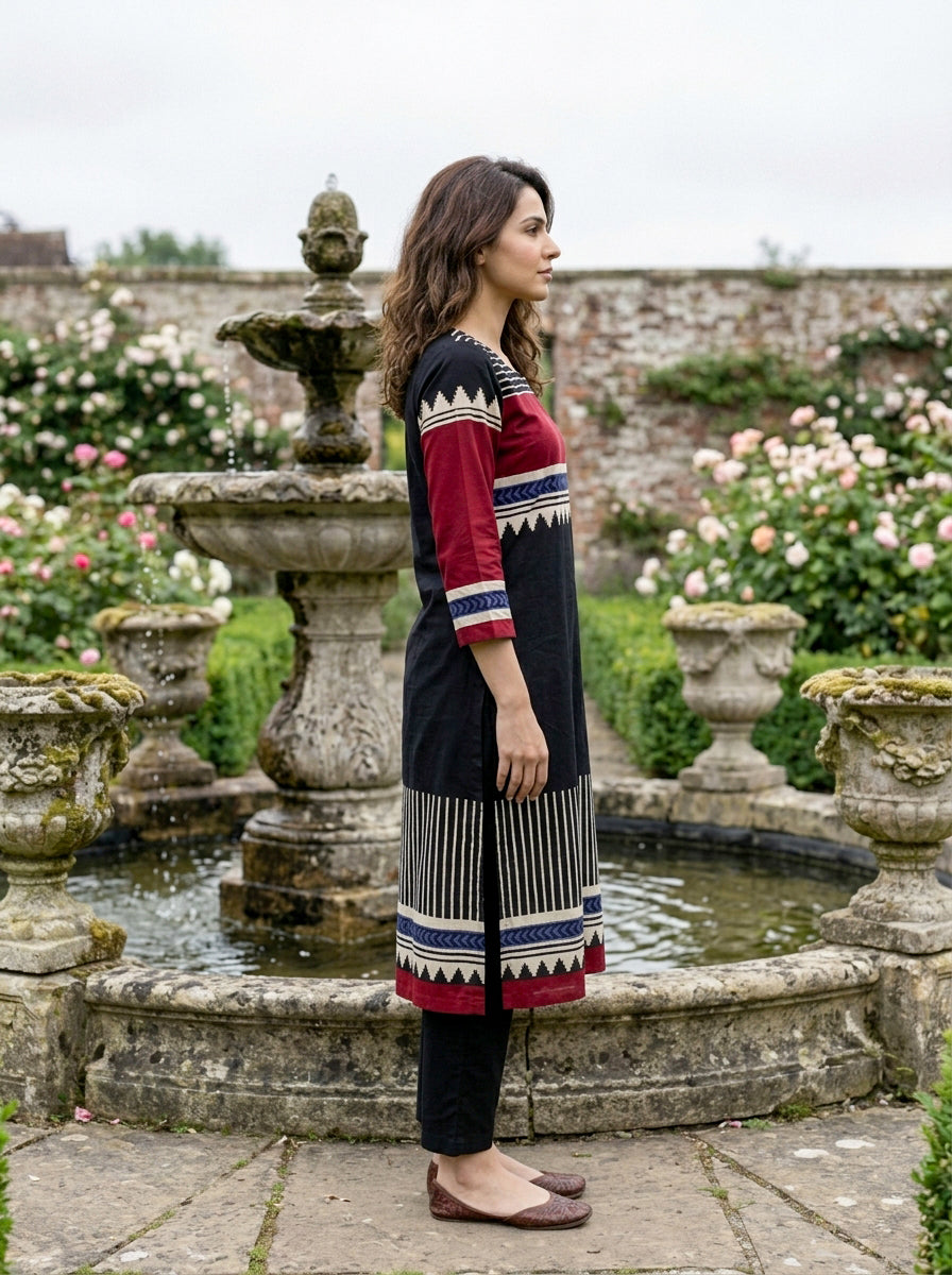 Side profile of woman in black, red, and blue tribal print kurta and black pants.